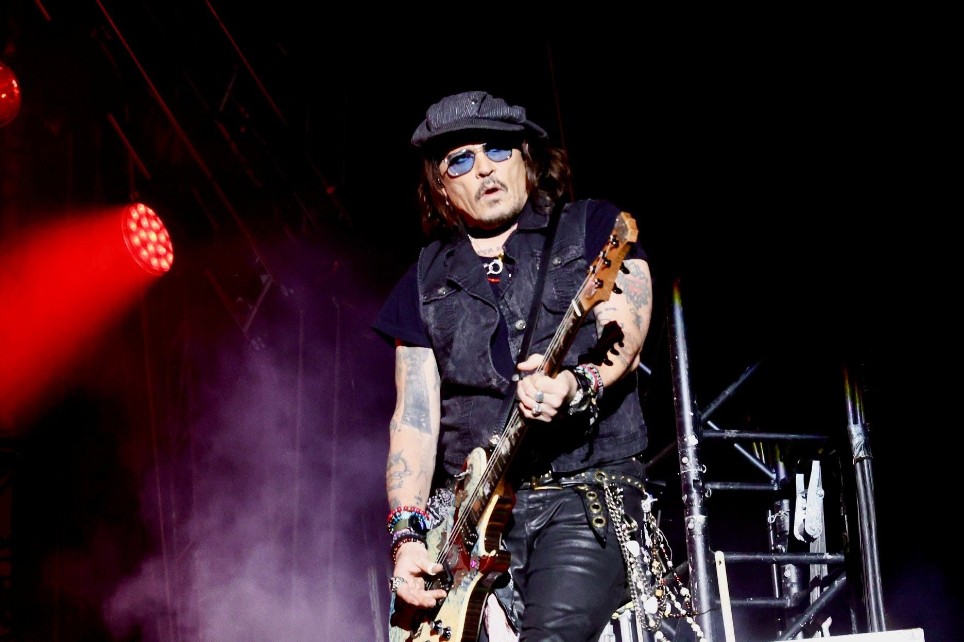 Gitarrist mit Mütze und Sonnenbrille spielt auf der Bühne bei einem Konzert der Hollywood Vampires.