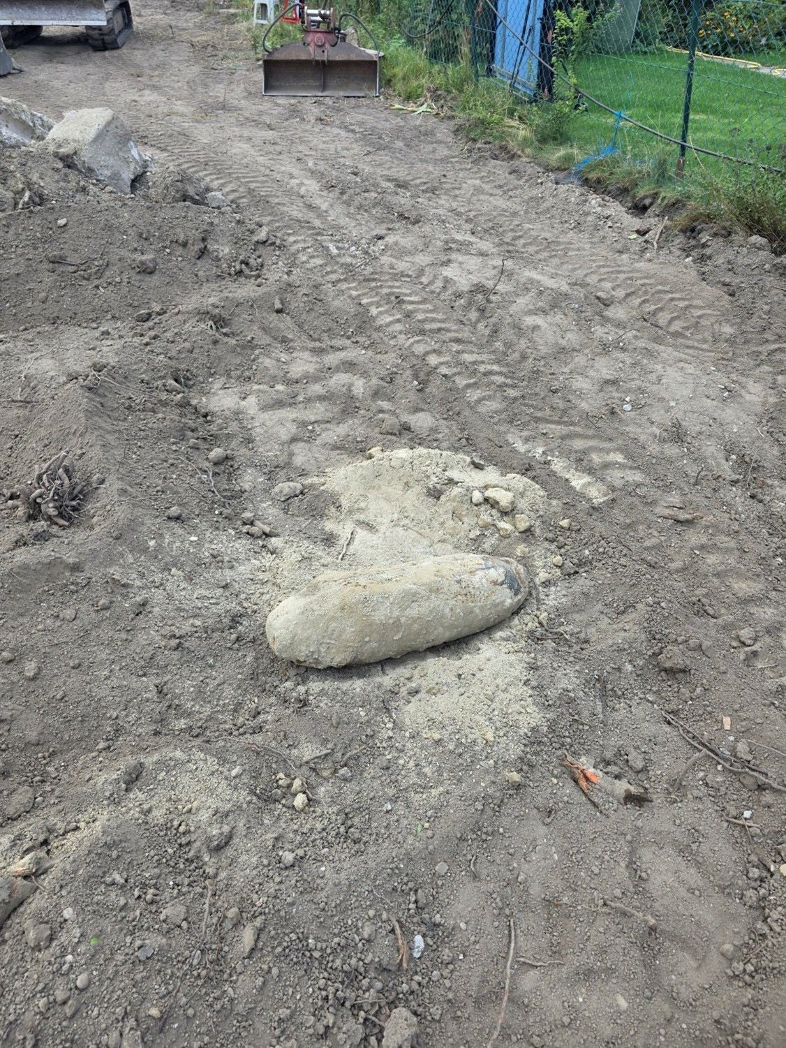 Eine Fliegerbombe liegt freigelegt auf einer Baustelle im Erdreich.