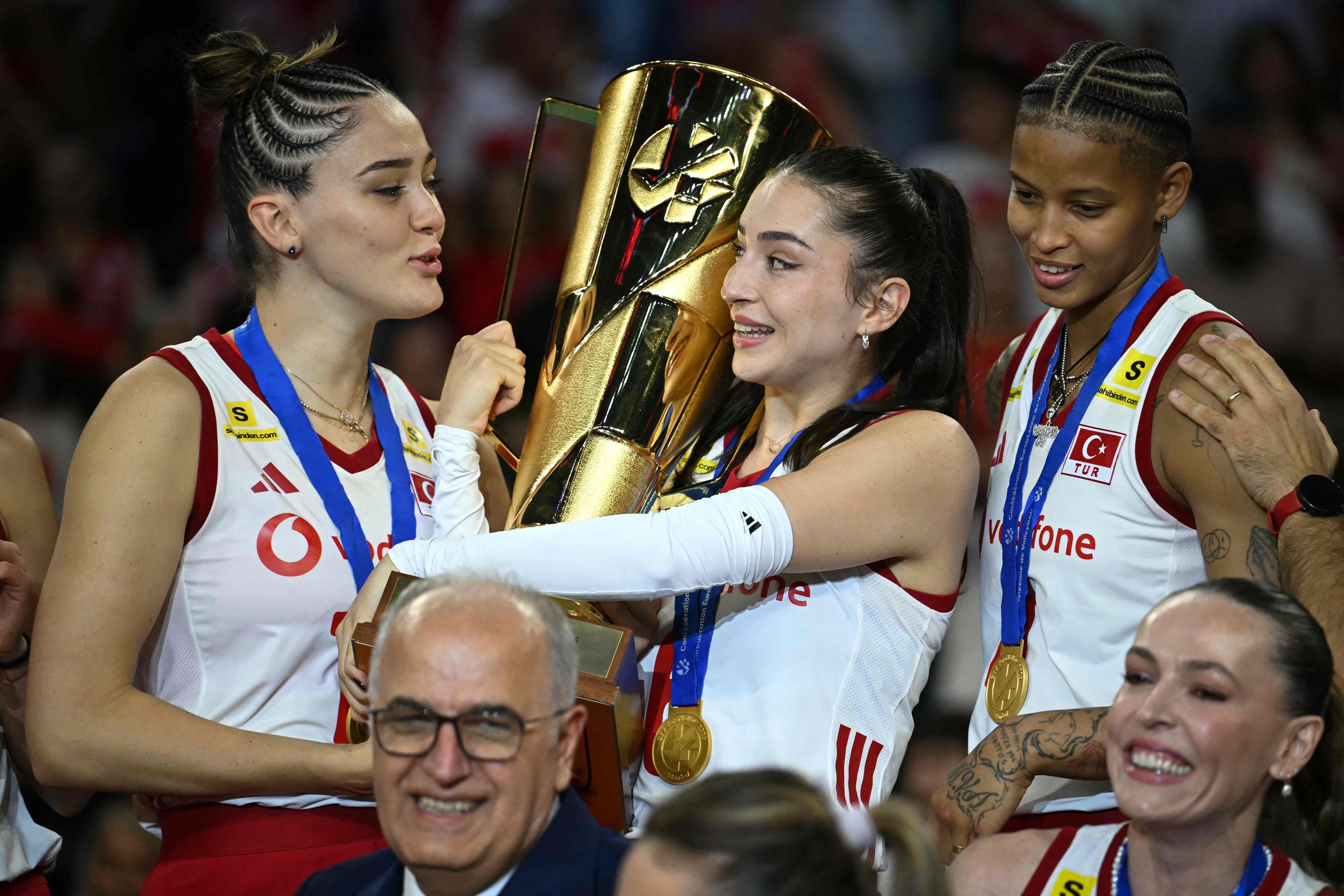 Drei türkische Volleyball-Nationalspielerinnen, darunter Zehra Güneş und Melissa Vargas, halten strahlend die goldene EM-Trophäe.