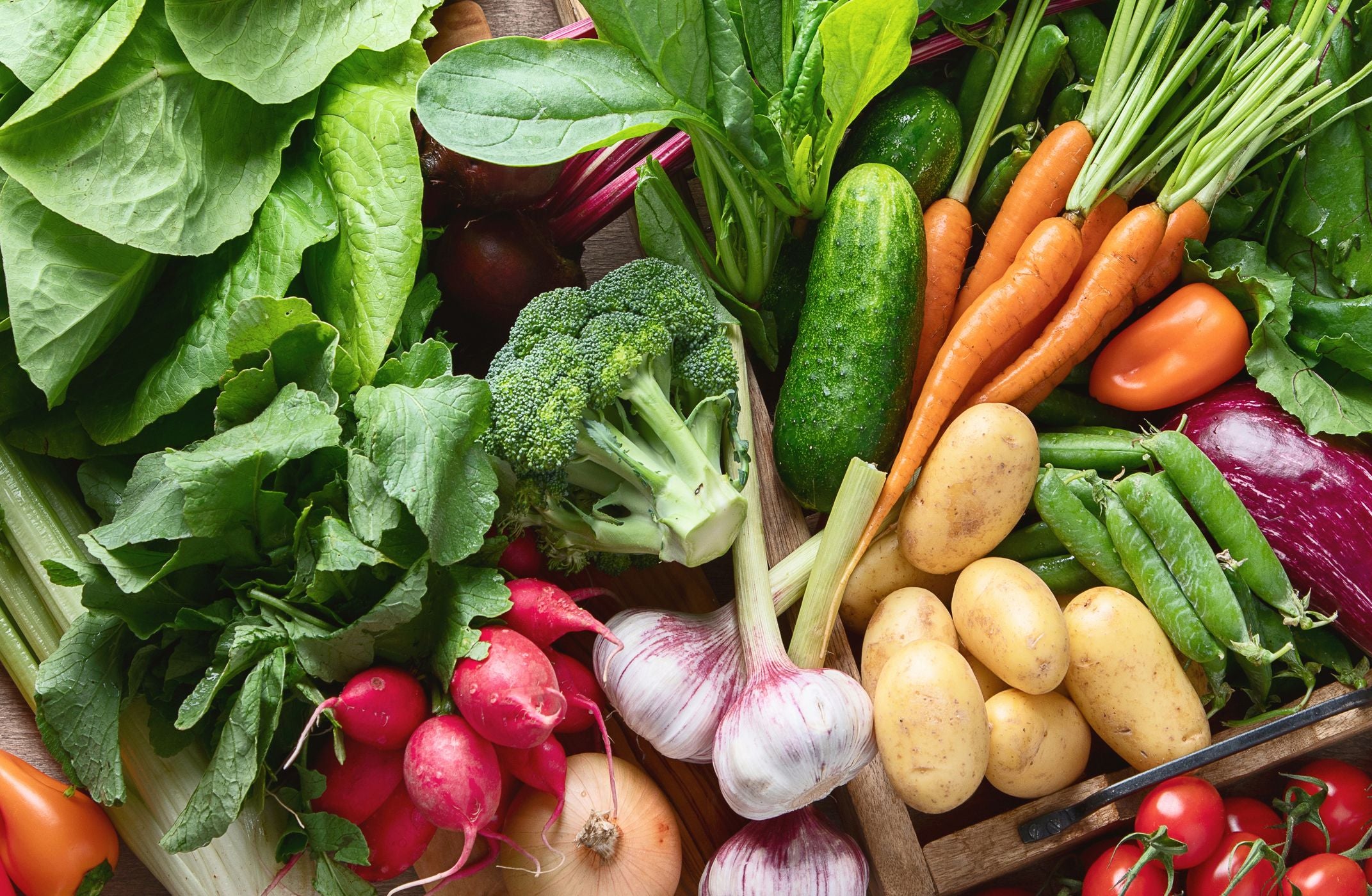 Verschiedene frische Gemüsesorten wie Karotten, Kartoffeln, Brokkoli und Salat nebeneinander.