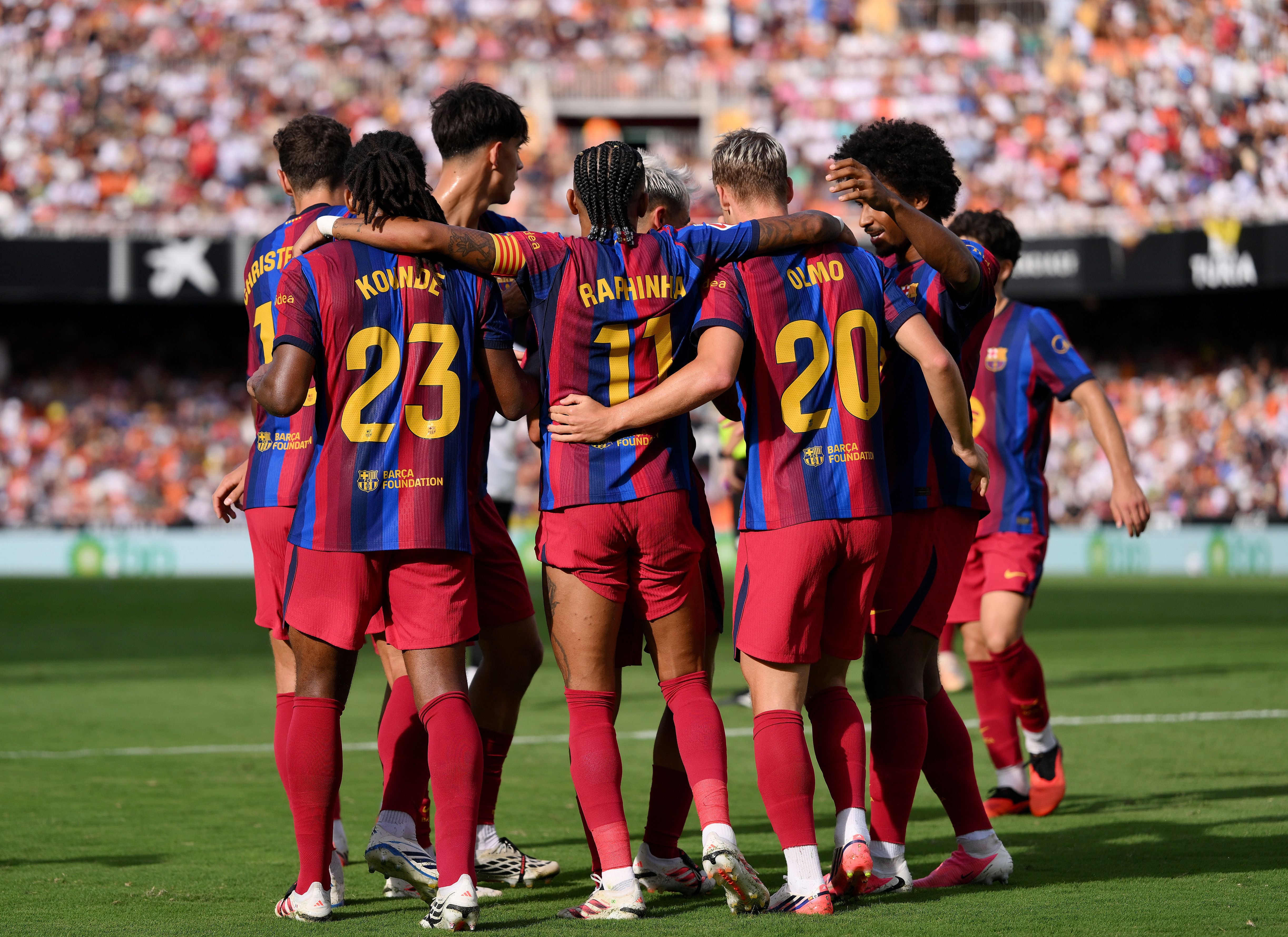 Barcelona-Spieler feiern gemeinsam ein Tor im Stadion, Zuschauer im Hintergrund.