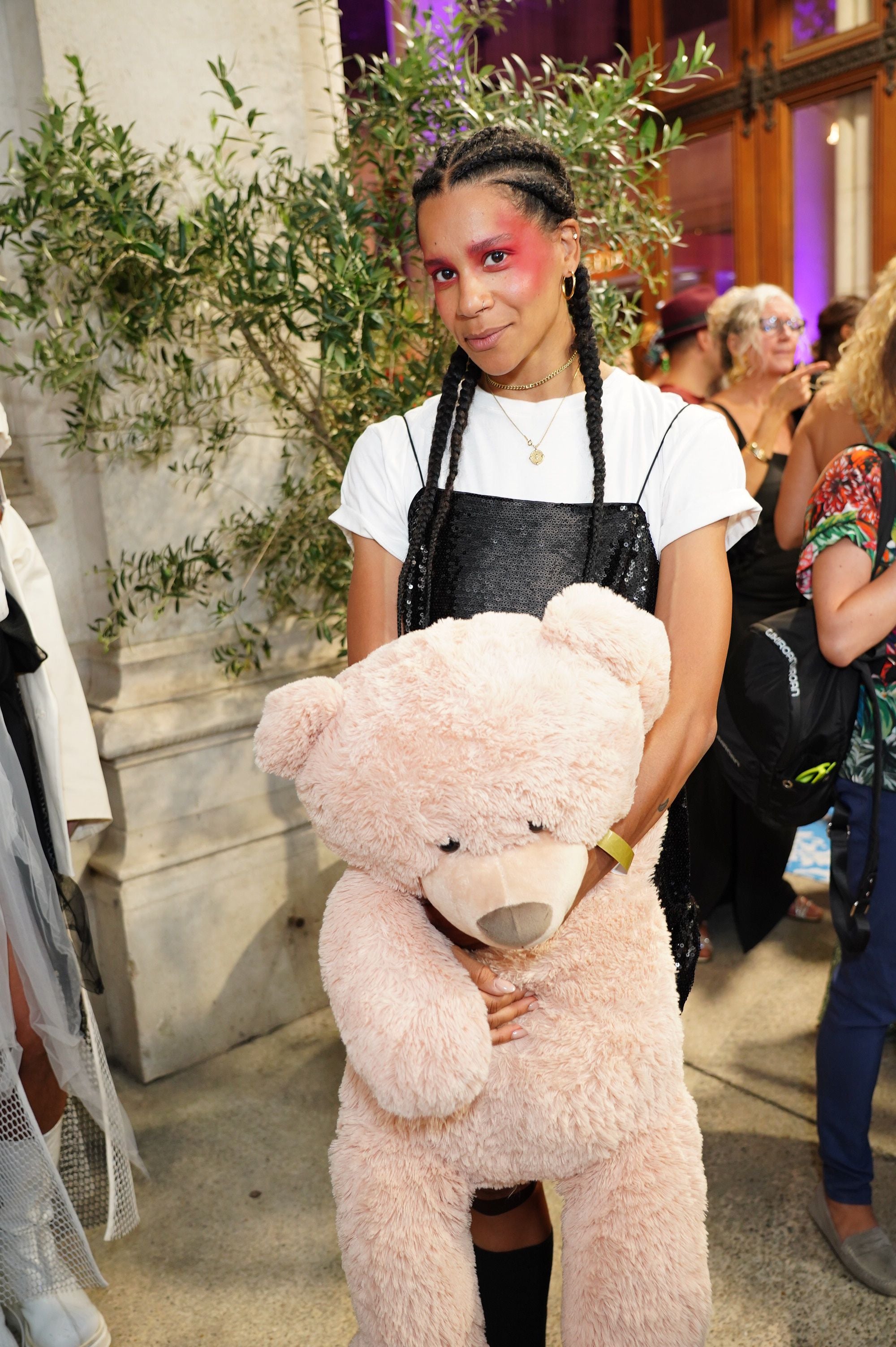 Frau mit auffälligem Make-up hält einen großen, rosa Teddybär beim Diversity Ball.