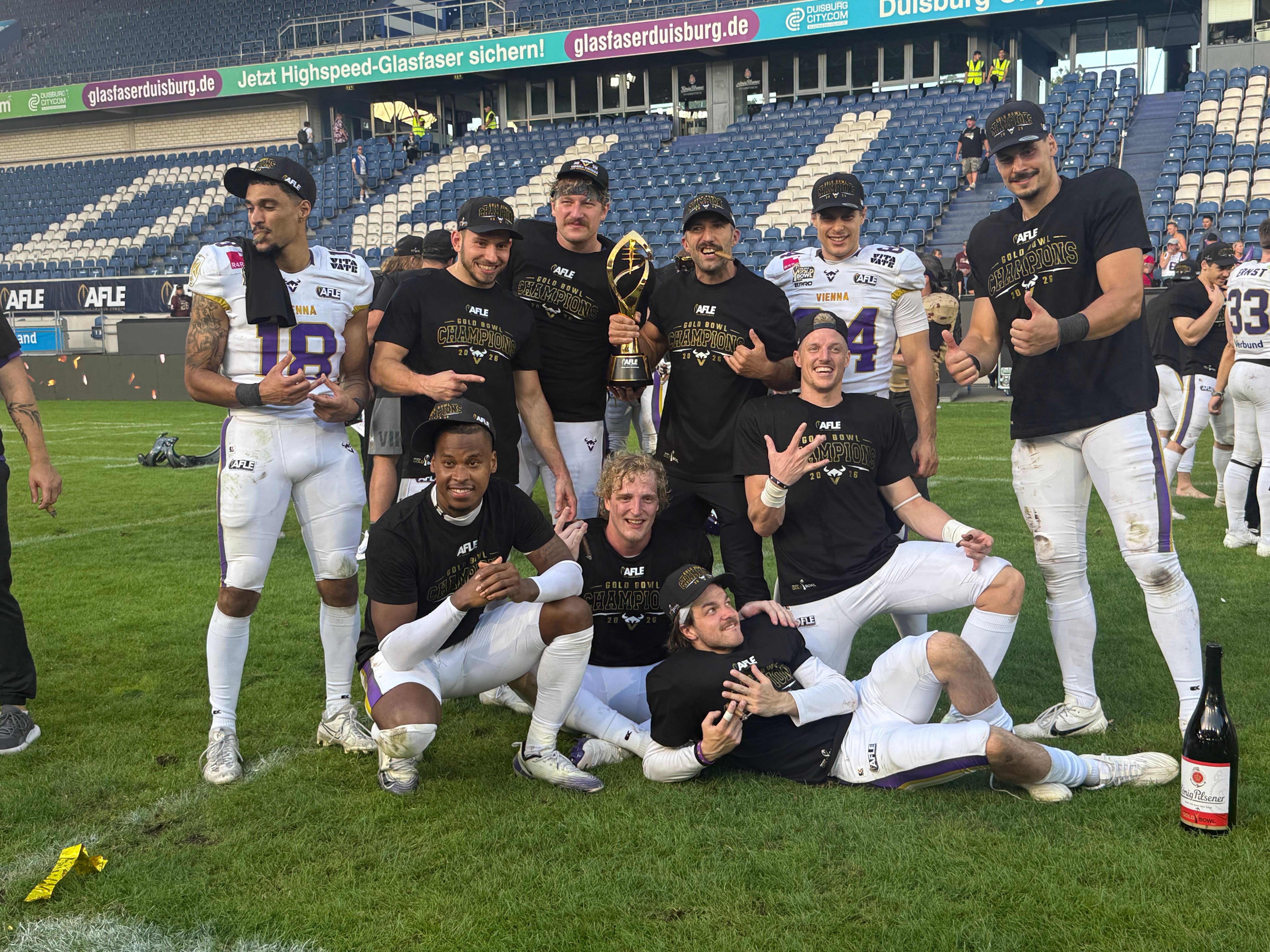 Eine Gruppe von Vikings-Footballspielern feiert auf dem Spielfeld mit einem Pokal.