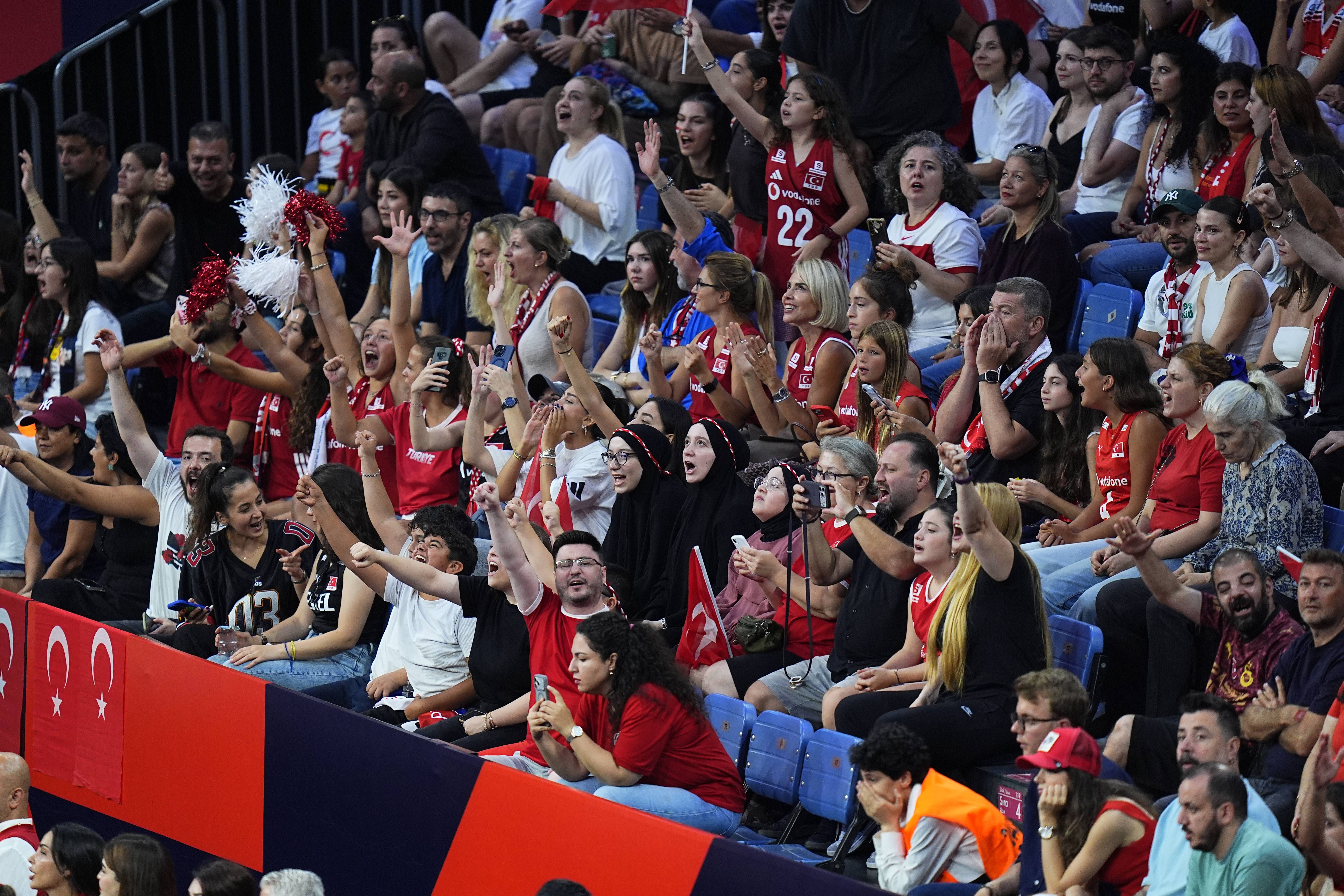 Zahlreiche türkische Fans in rot-weißer Kleidung jubeln auf den Rängen der Halle mit erhobenen Arme und schwenken Flaggen.