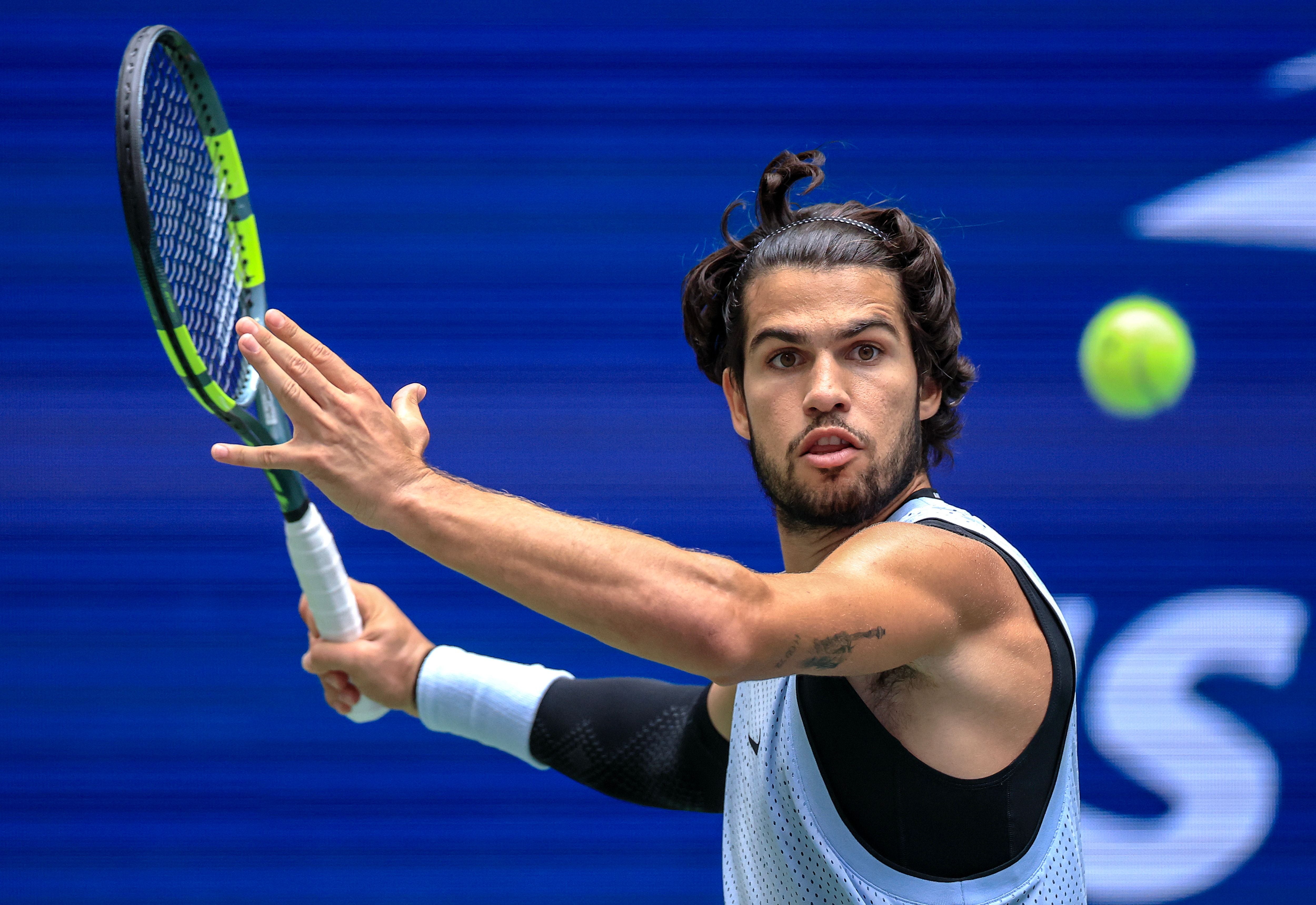 Der spanische Tennisprofi Carlos Alcaraz holt mit einem Schläger in der Hand zu einer Vorhand auf dem Hartplatz aus.