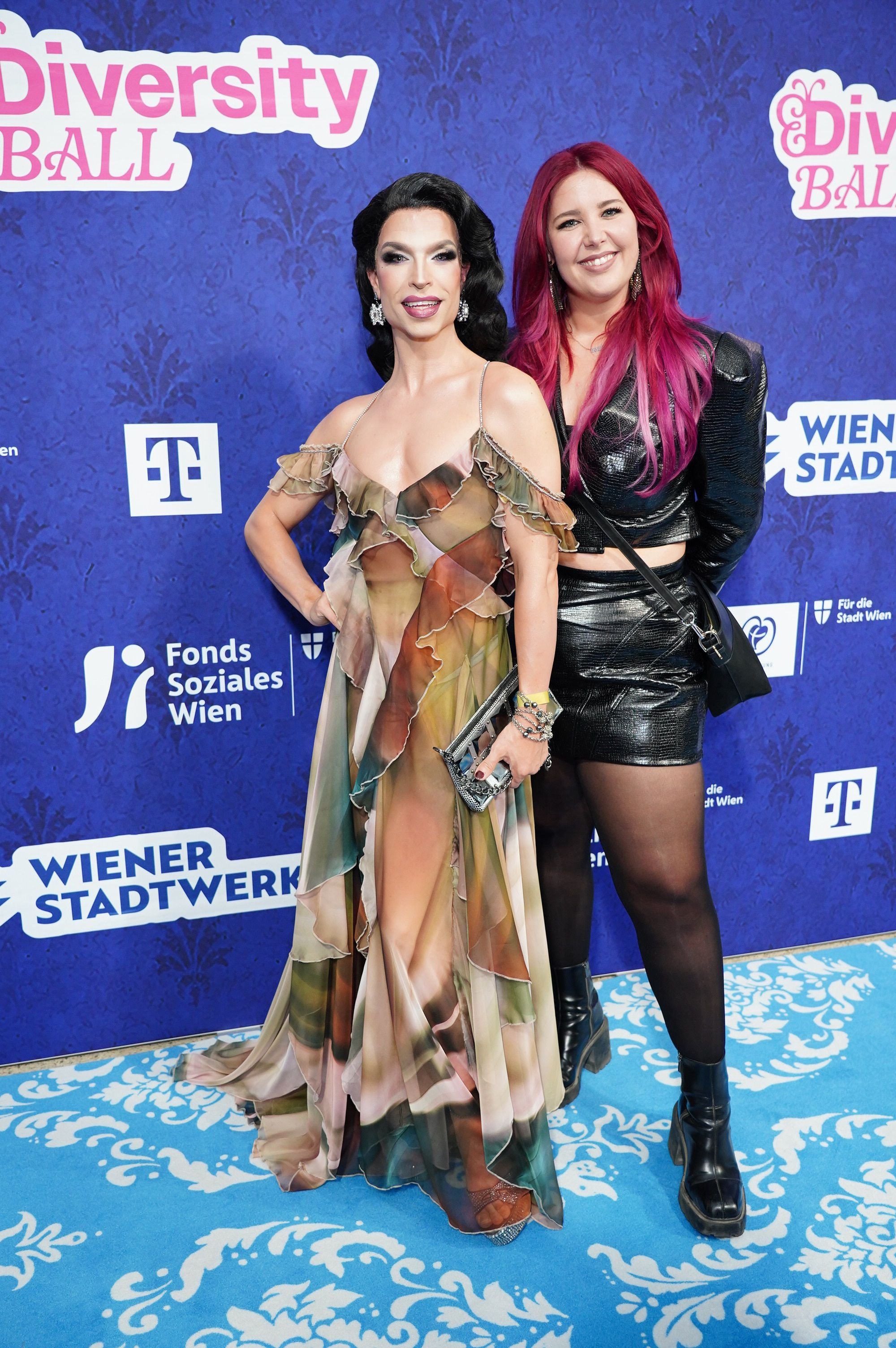 Zwei Personen posieren elegant auf dem blauen Teppich beim Diversity Ball in Wien.