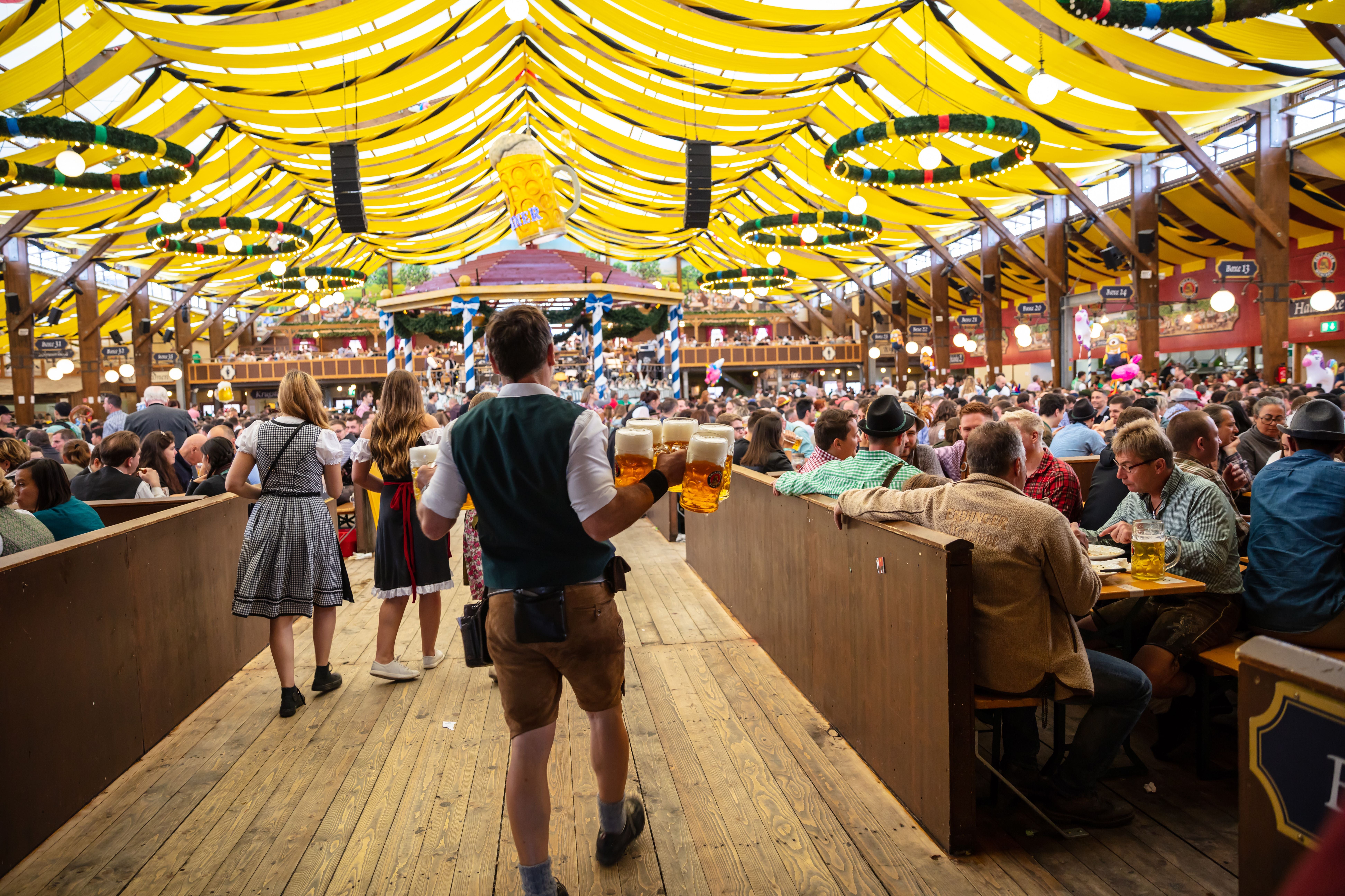 Ein Kellner trägt Bierkrüge in einem vollen Festzelt auf dem Münchner Oktoberfest.