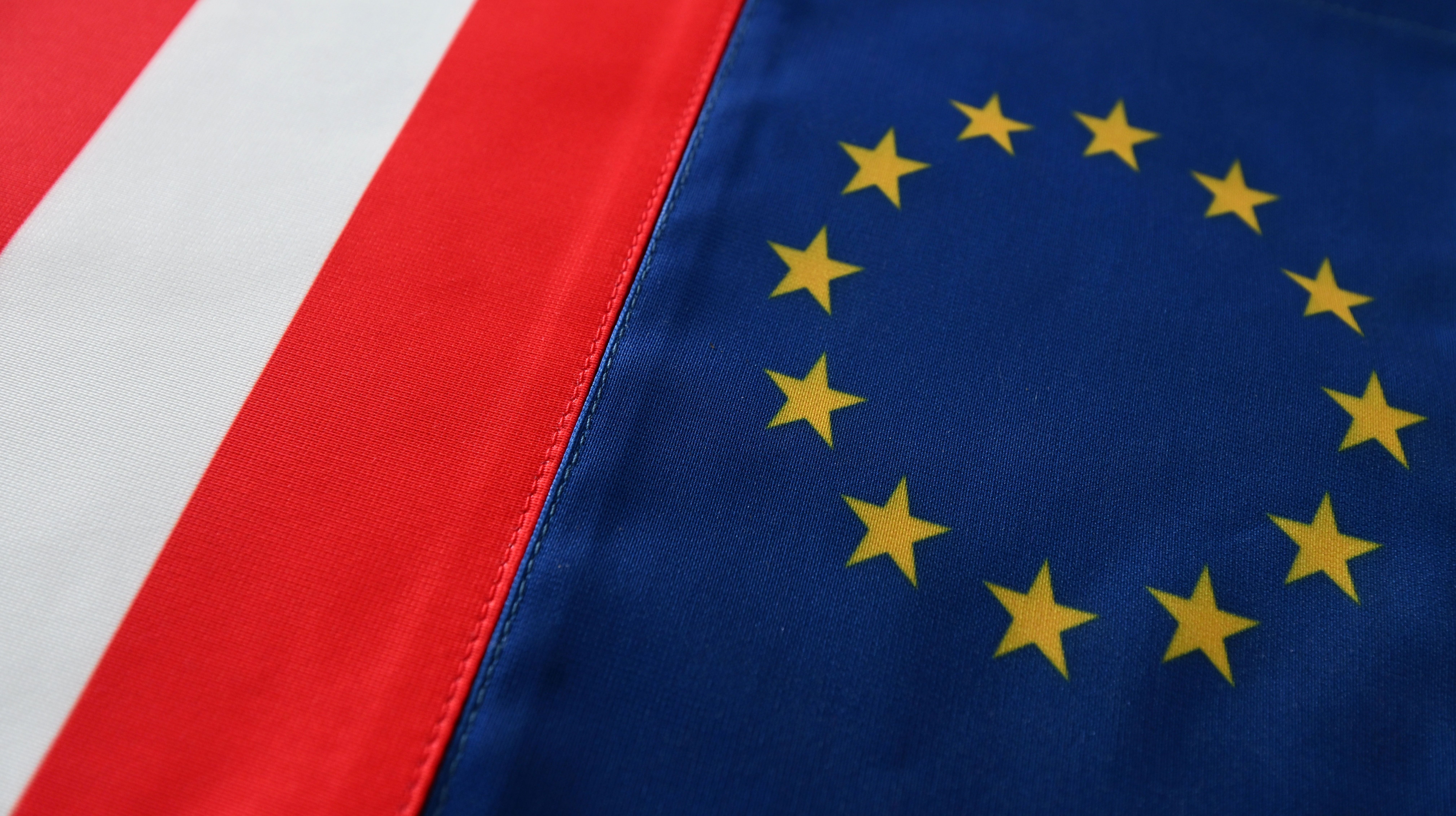 Österreichische Flagge und EU-Flagge liegen nebeneinander und sind im Anschnitt zu sehen.