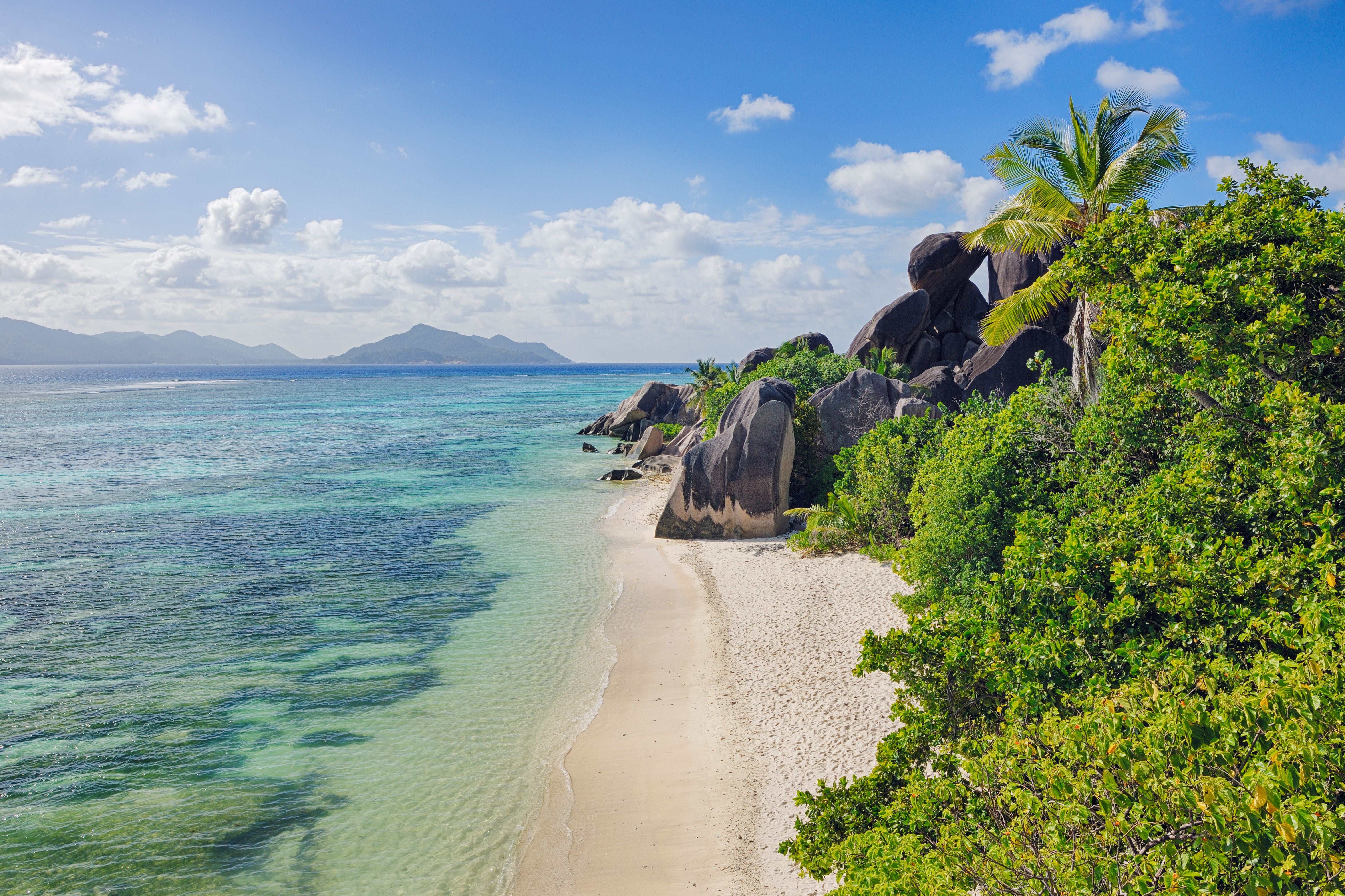 Tropischer Strand mit Felsen, Palmen und türkisfarbenem Wasser auf La Digue, Seychellen.