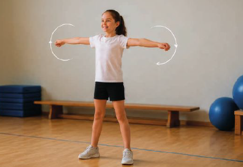 Mädchen macht Armkreisen in Sportkleidung in einer Turnhalle.