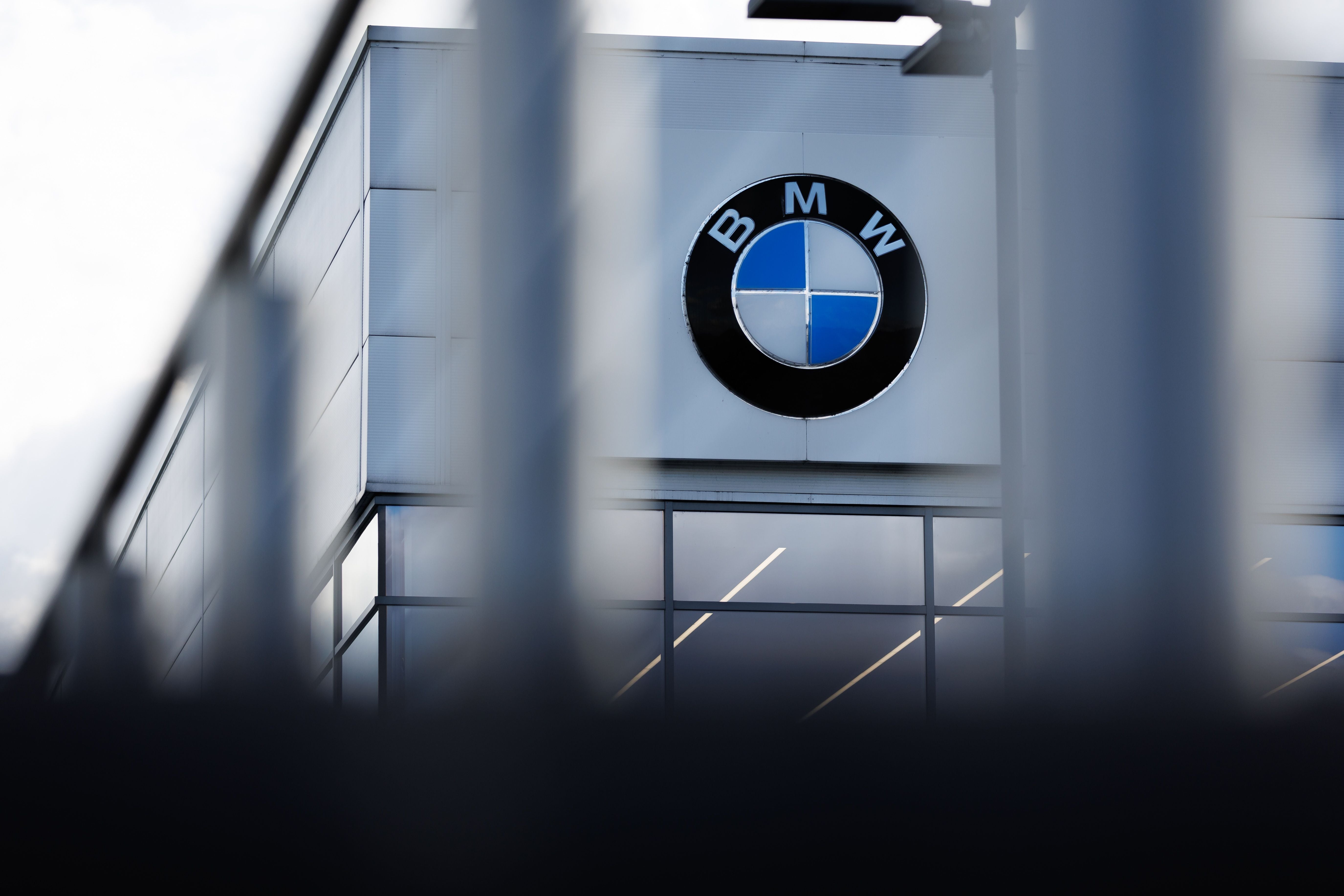 BMW-Logo an der Fassade eines Autohauses mit modernen Glasfenstern.