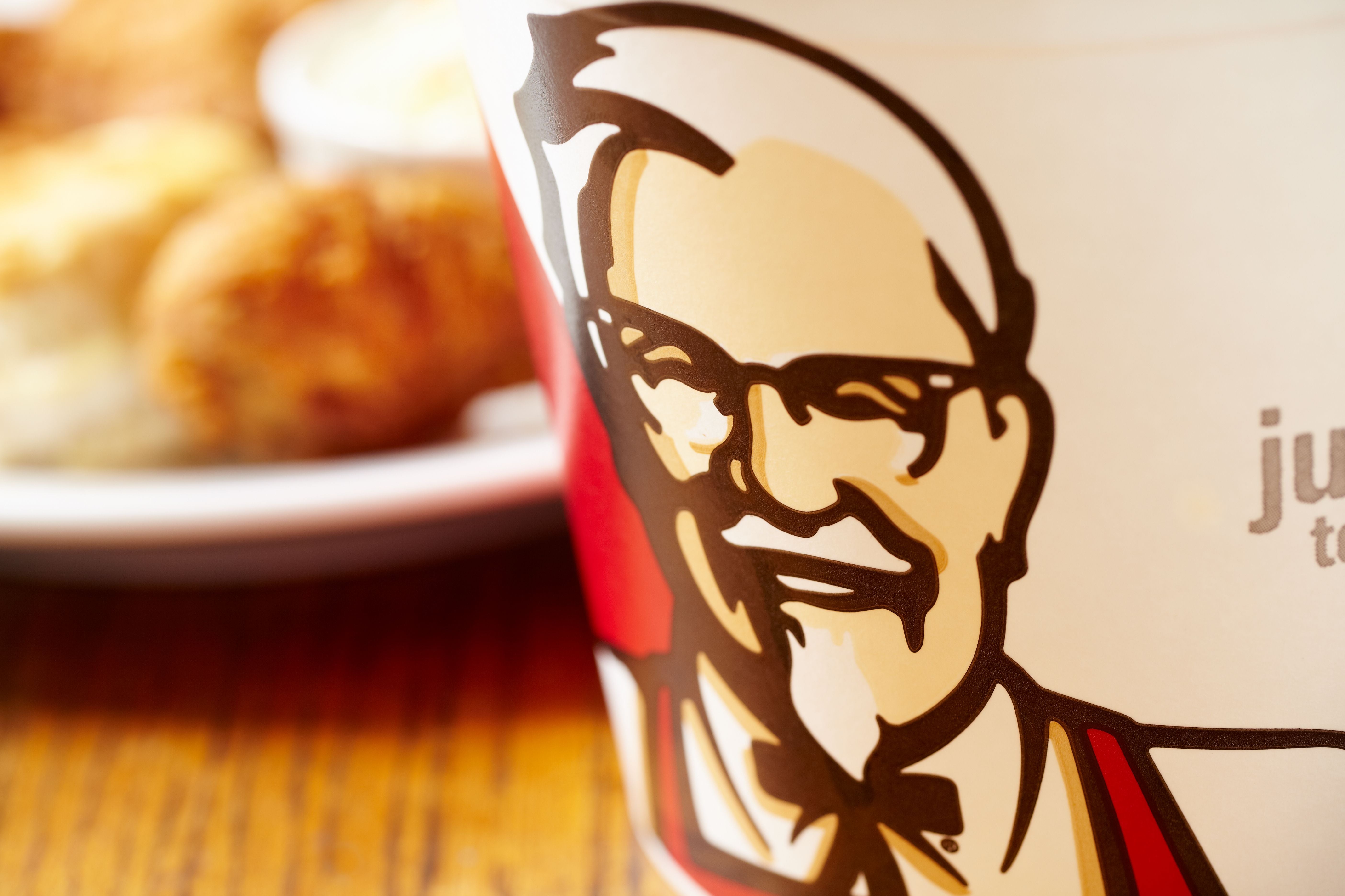 Nahaufnahme eines KFC-Bechers mit dem berühmten Colonel-Sanders-Logo.