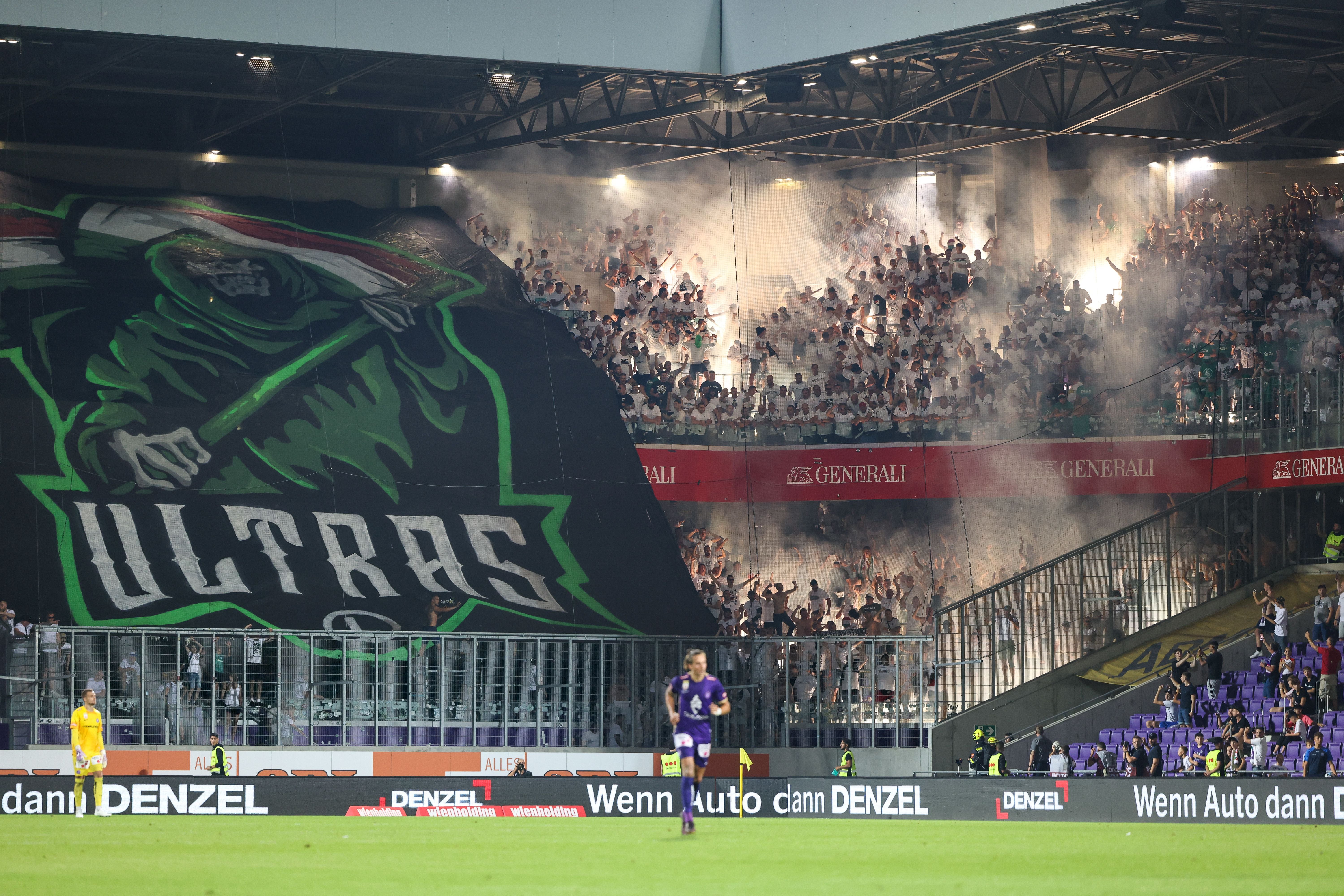 Legia-Warschau-Fans mit riesigem „Ultras”-Banner und Rauch im Fußballstadion.