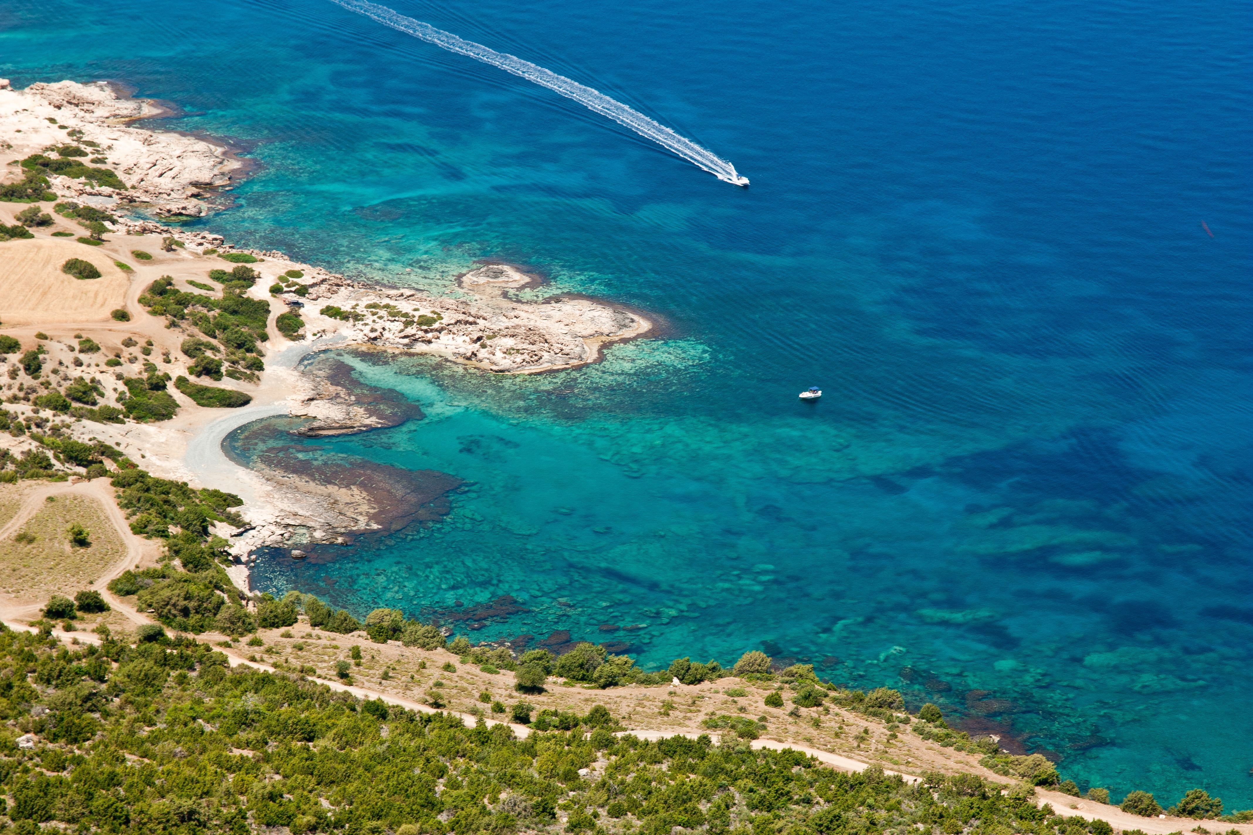 Luftaufnahme der Halbinsel Akamas mit klarem türkisblauem Meer und Booten an der Küste.