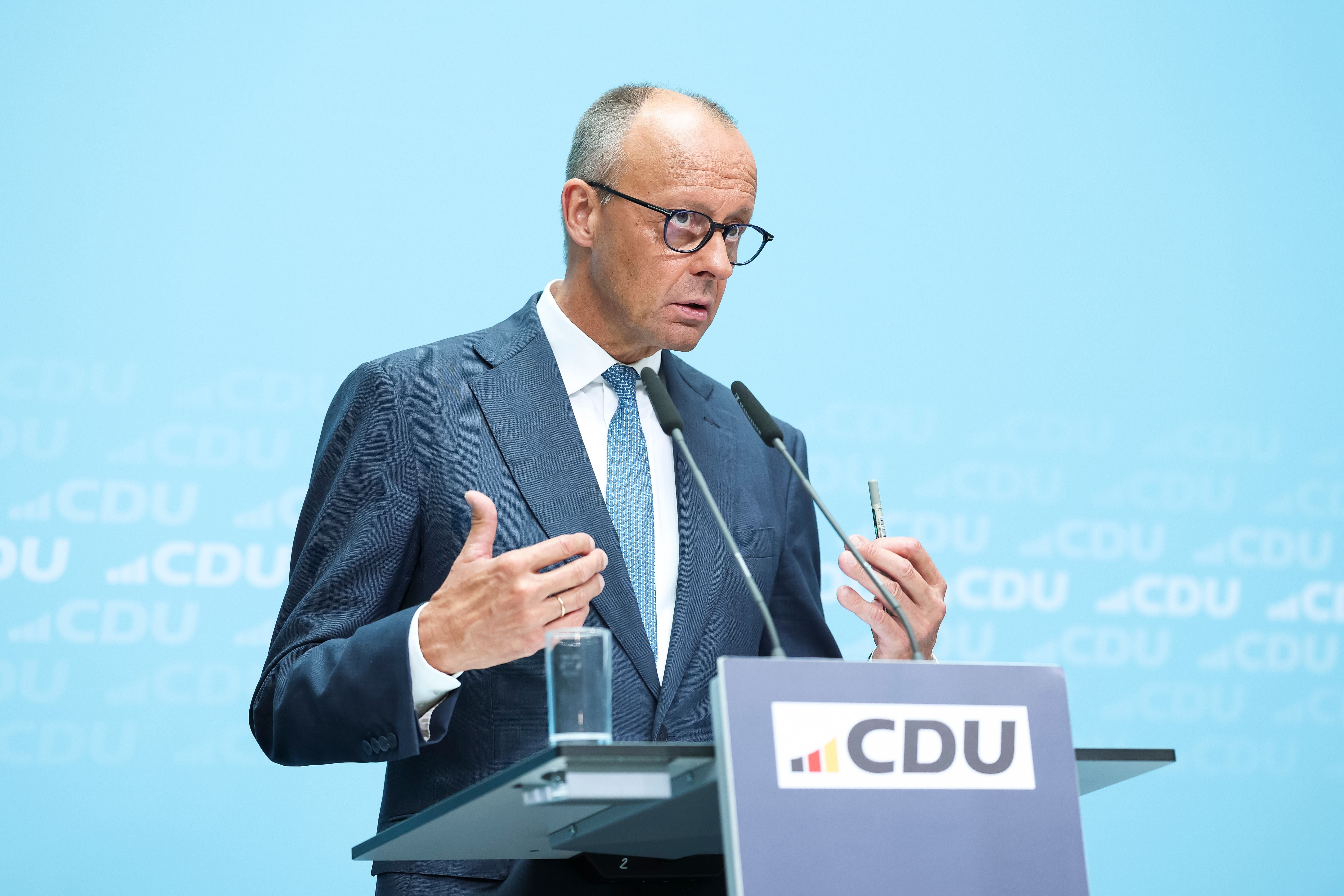 Ein Mann im Anzug spricht bei einer CDU-Pressekonferenz vor Mikrofonen und Pult.