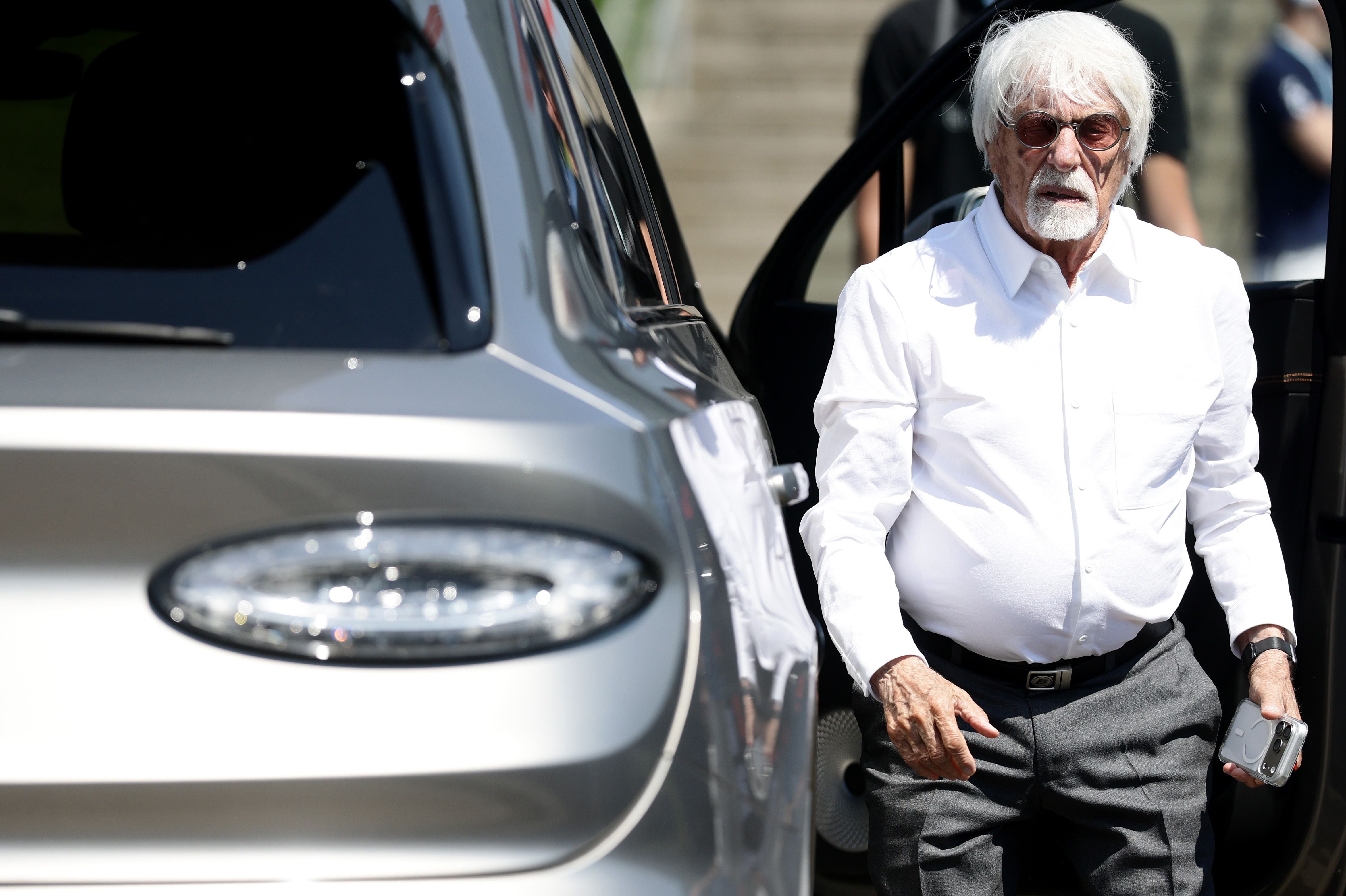 Älterer Mann mit weißem Hemd und Sonnenbrille steigt aus einem Auto aus.