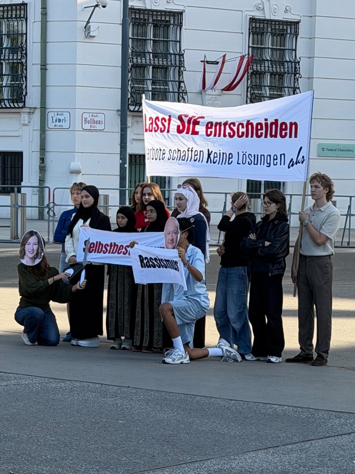 Gruppe junger Menschen mit Bannern protestiert vor dem Kanzleramt in Wien.