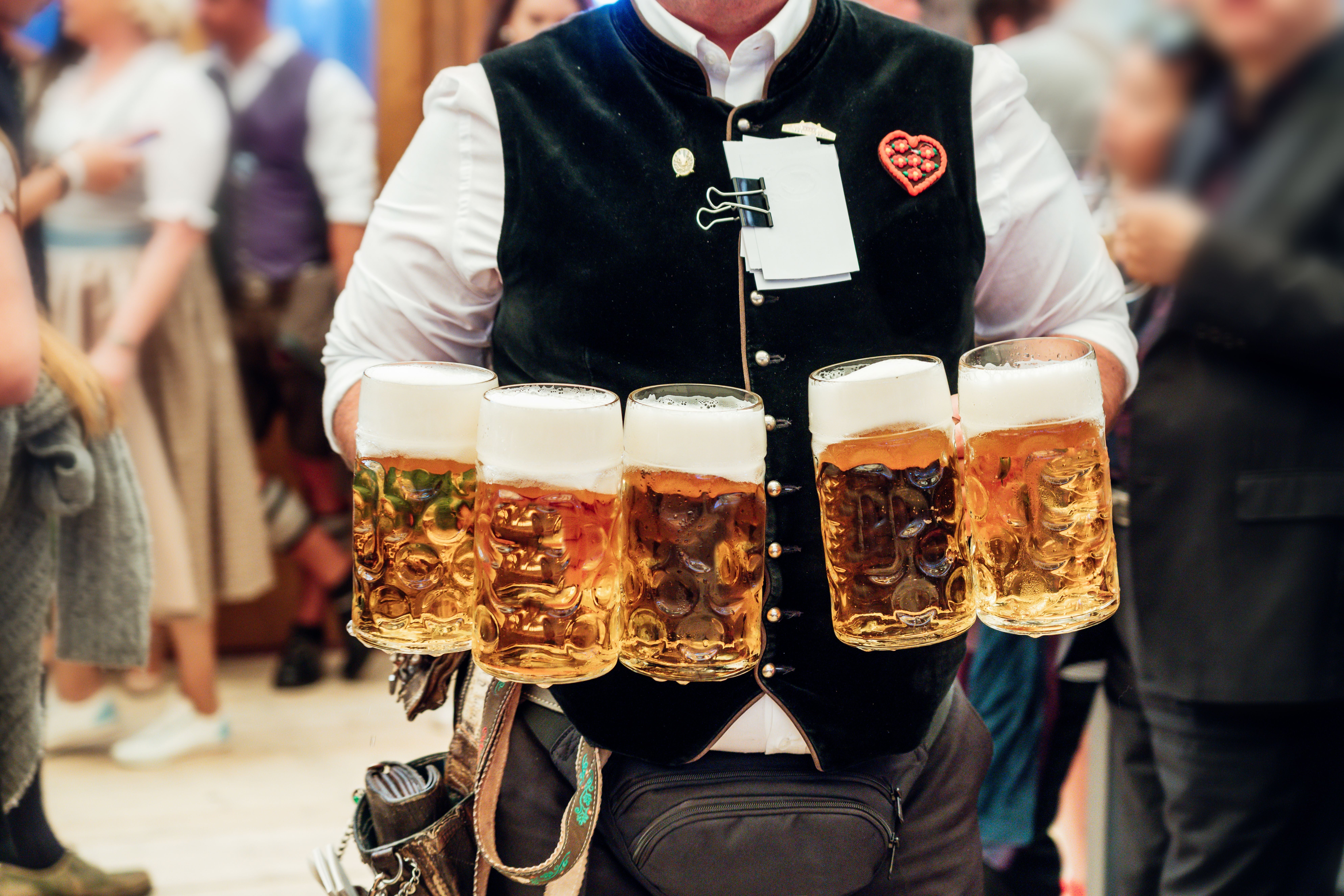 Kellner trägt fünf große Bierkrüge auf dem Oktoberfest in München.