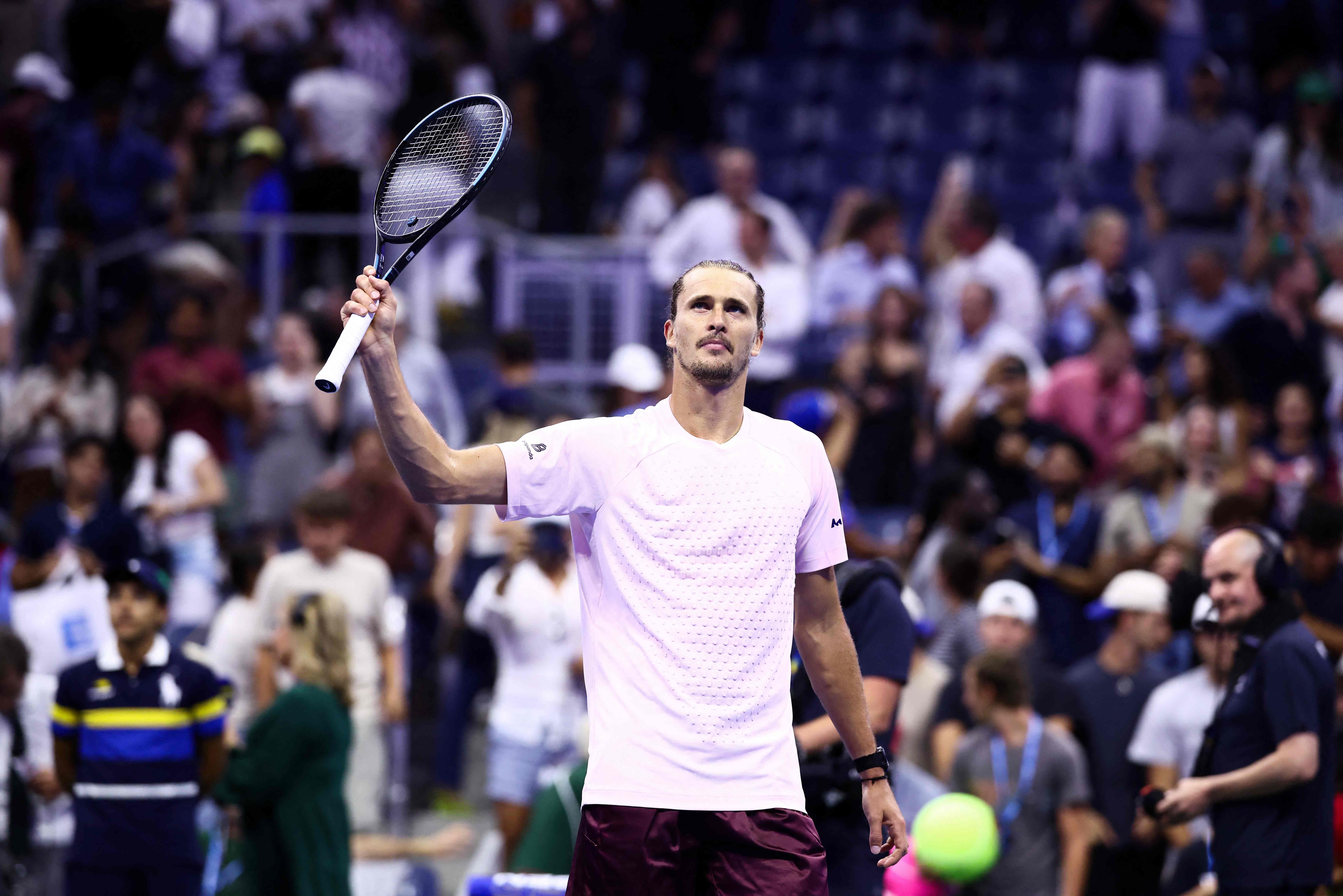 Ein Tennisspieler jubelt mit erhobenem Schläger vor begeistertem Publikum auf dem Tennisplatz.