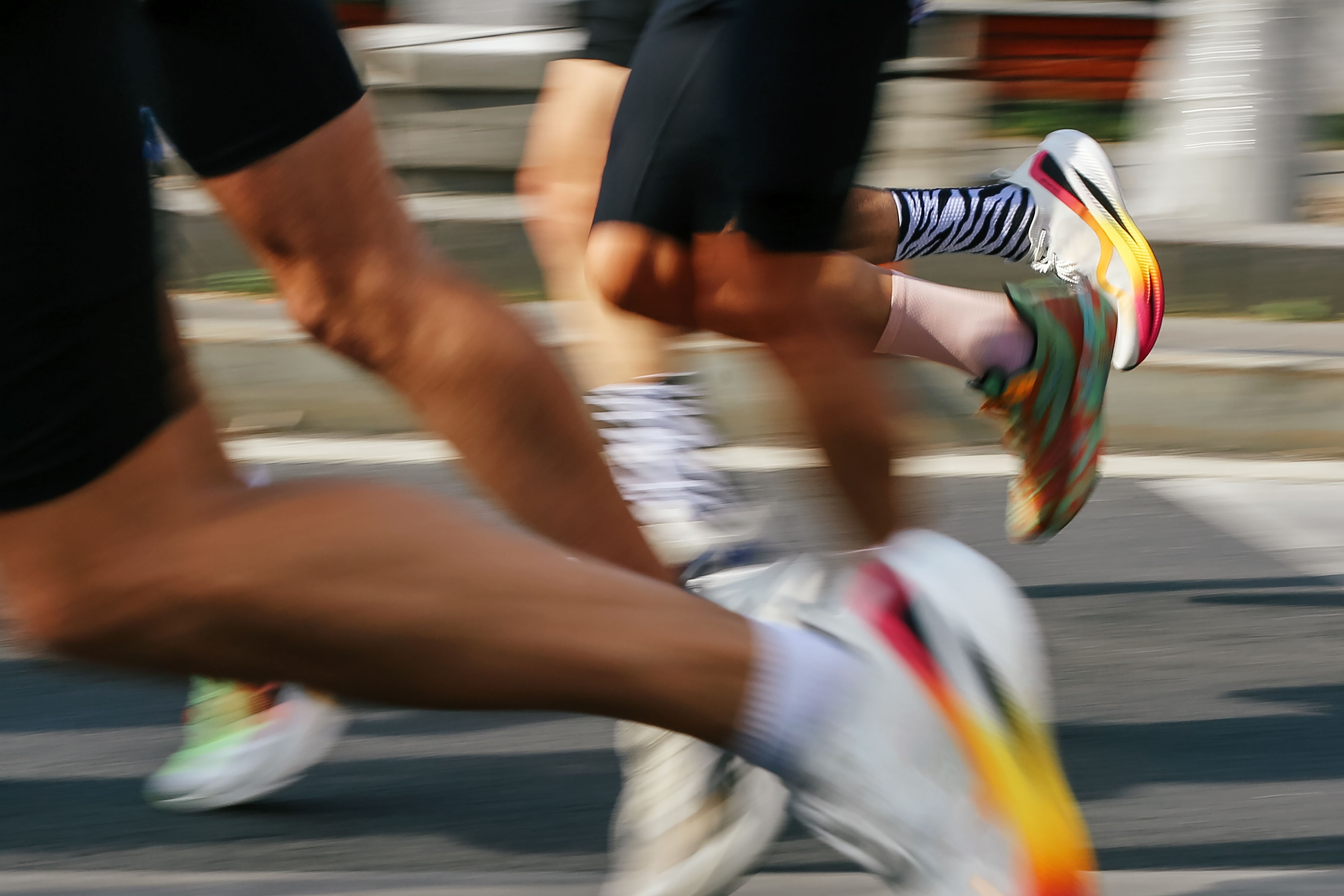 Mehrere Läufer in Bewegung bei einem Straßenmarathon aus der Seitenperspektive fotografiert.