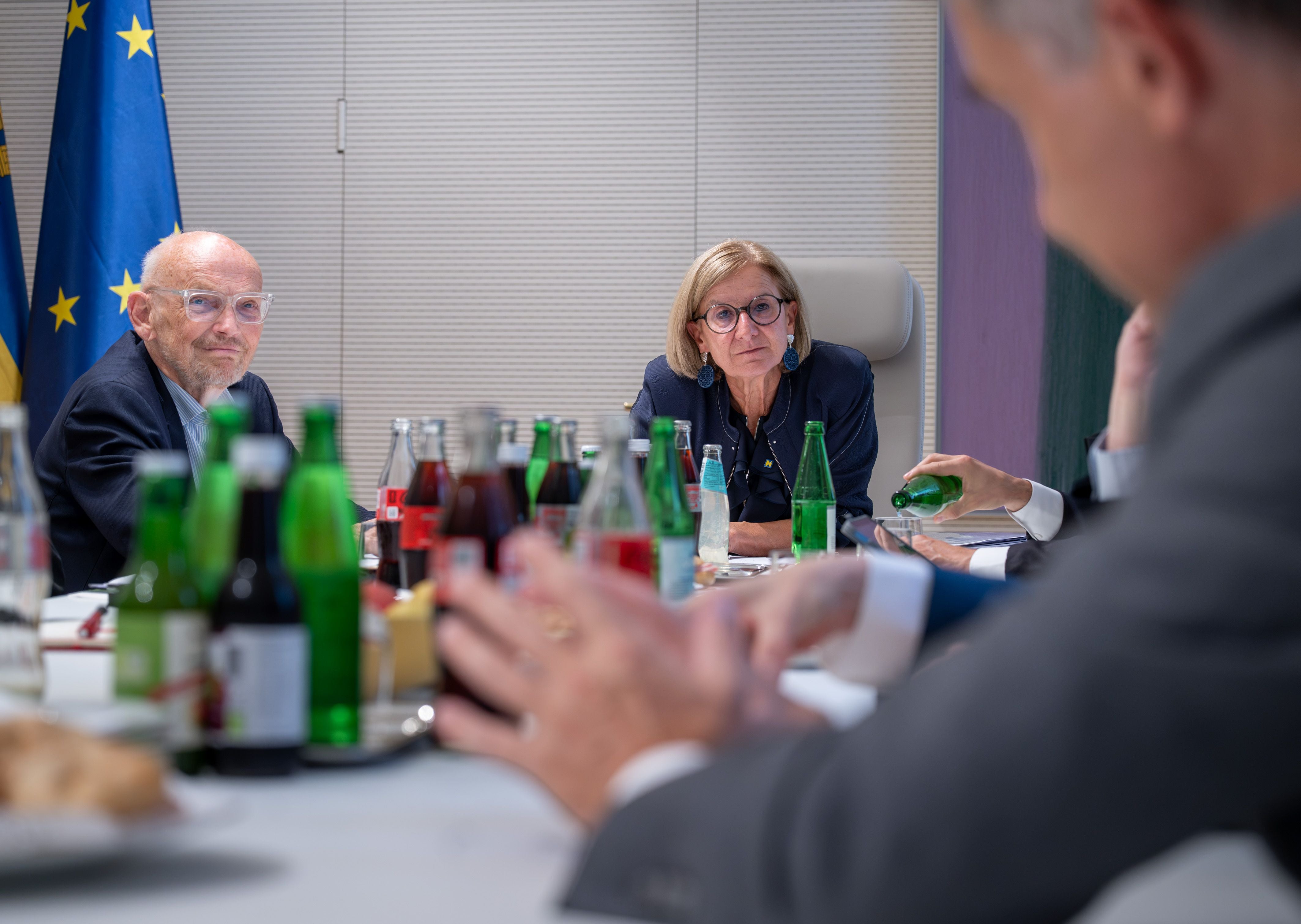 Mehrere Personen sitzen bei einem Gespräch mit Getränken an einem Konferenztisch.