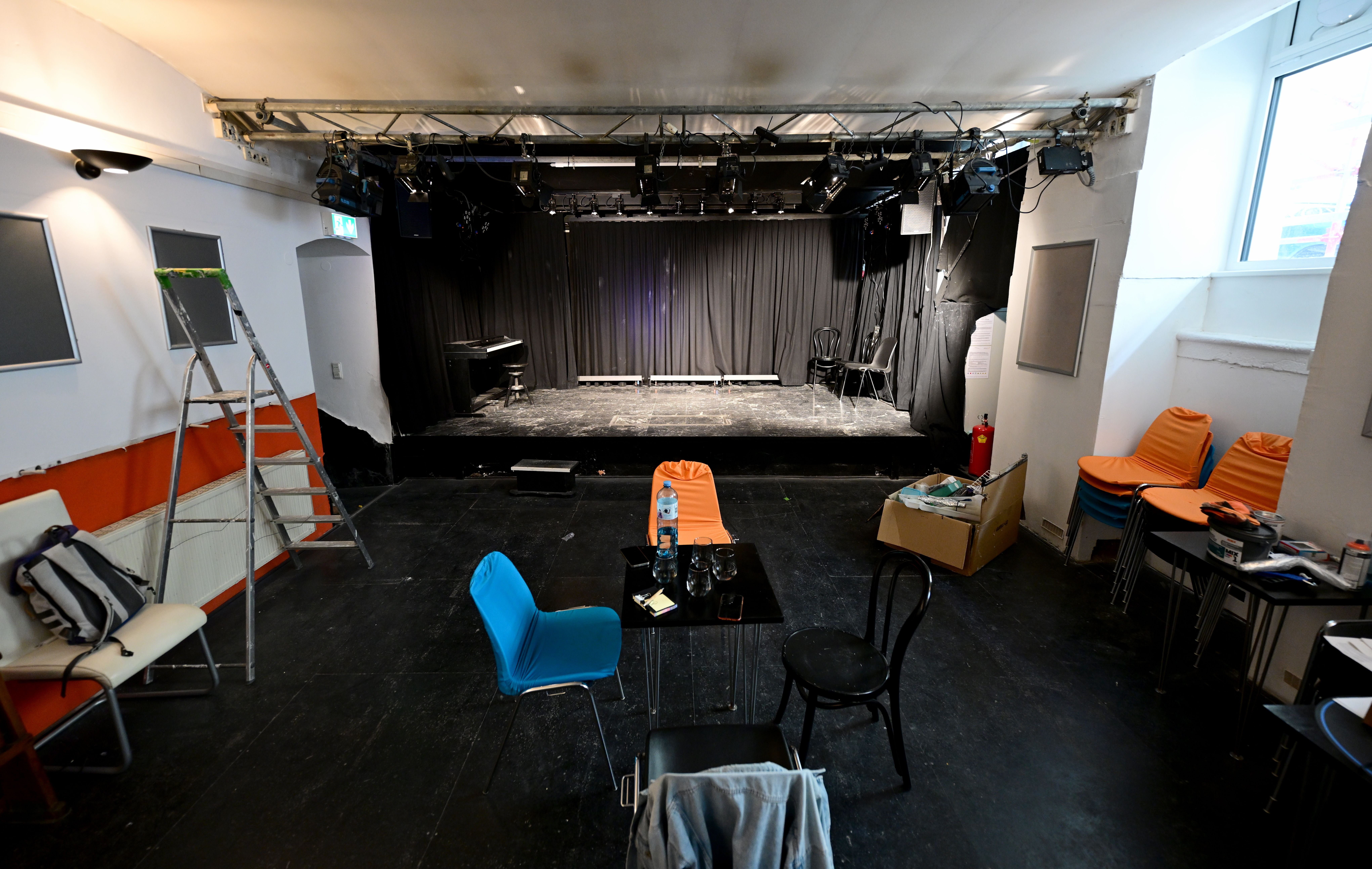 Blick auf eine leere Bühne im Löblichtheater Alsergrund, davor Stühle und Tische.