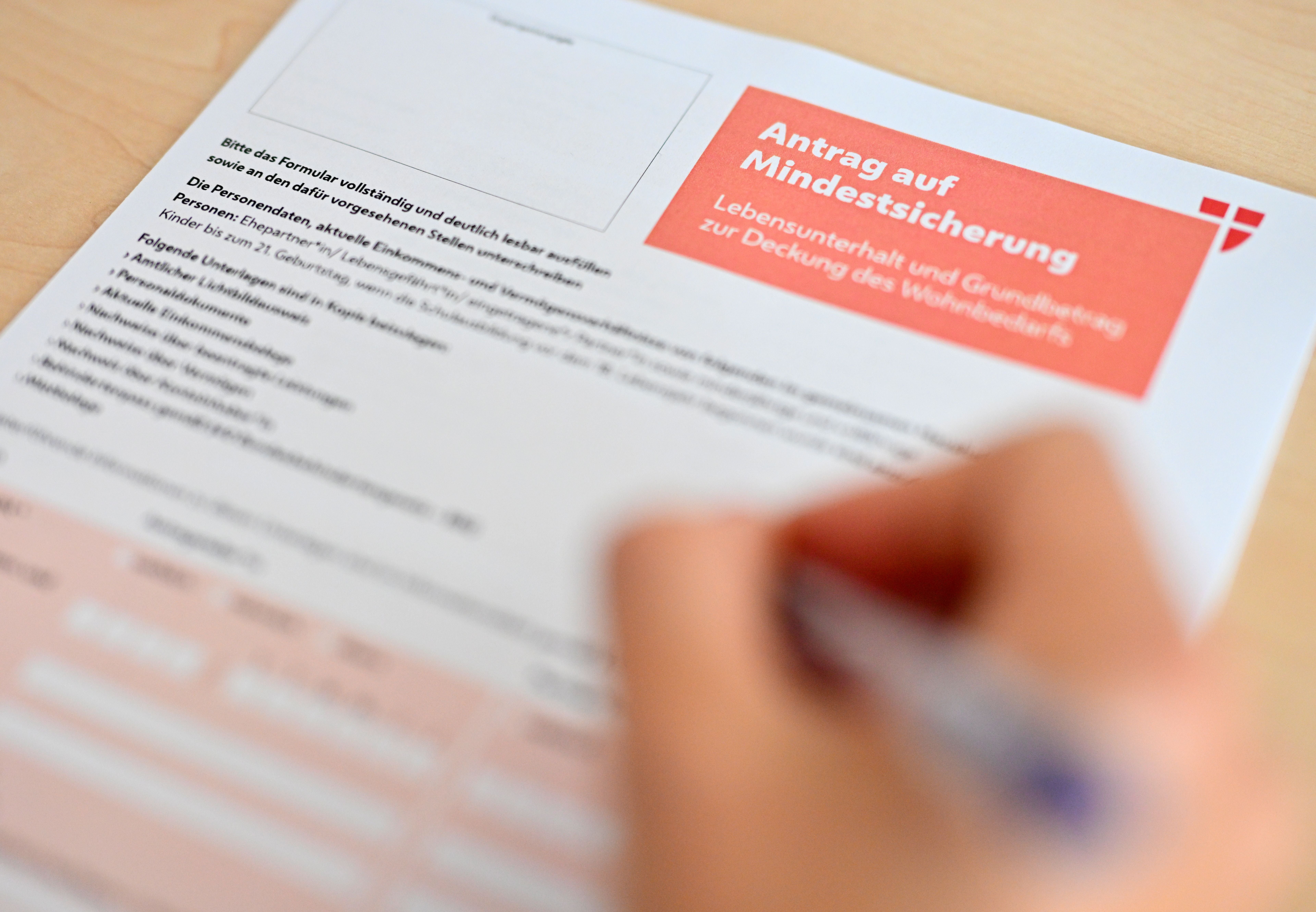 Ein Hand hält einen Stift und füllt ein Formular für einen Antrag auf Mindestsicherung in Wien aus.