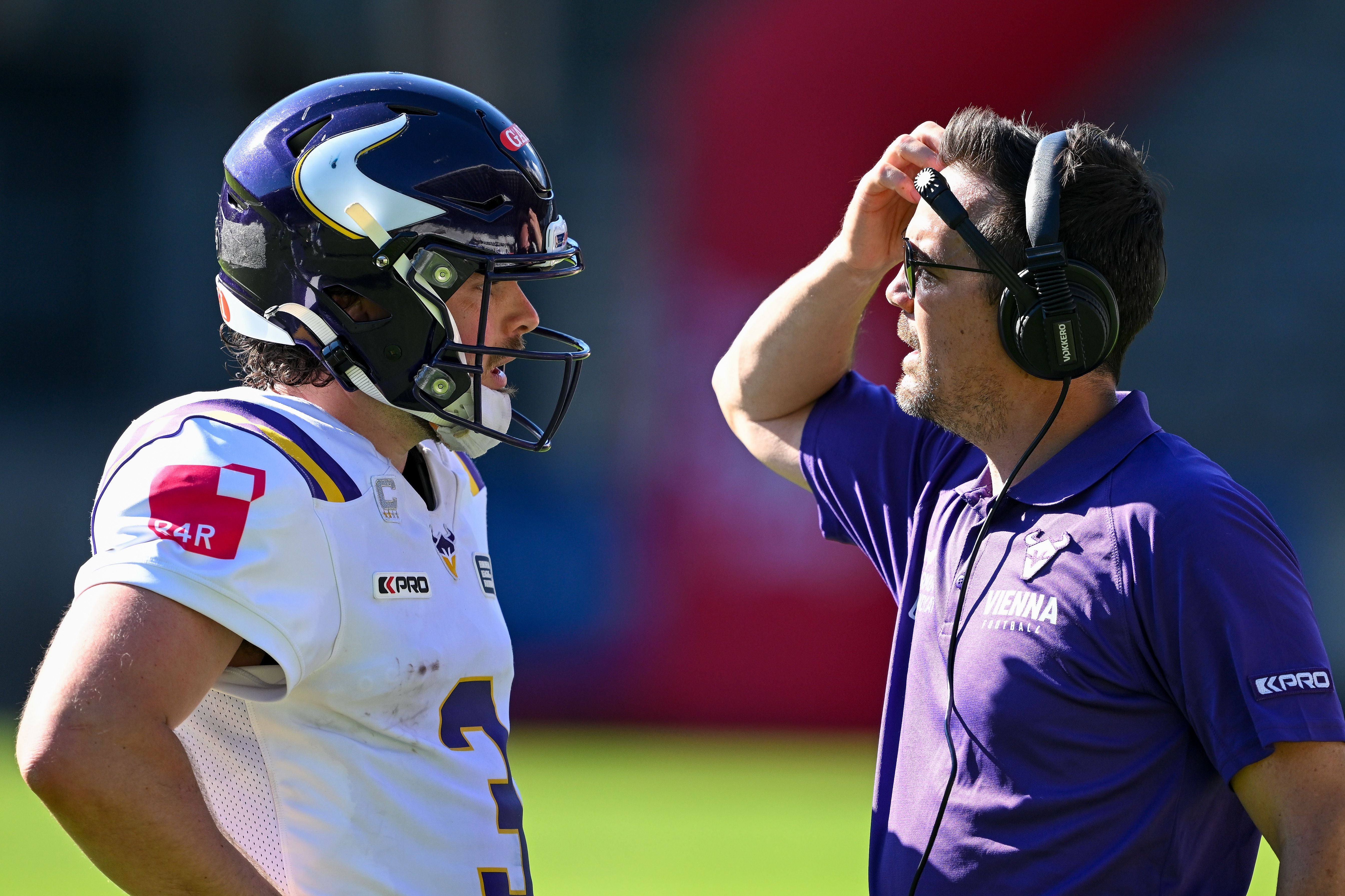 Ein Footballspieler und ein Trainer der Vienna Vikings sprechen sich am Spielfeldrand ab.