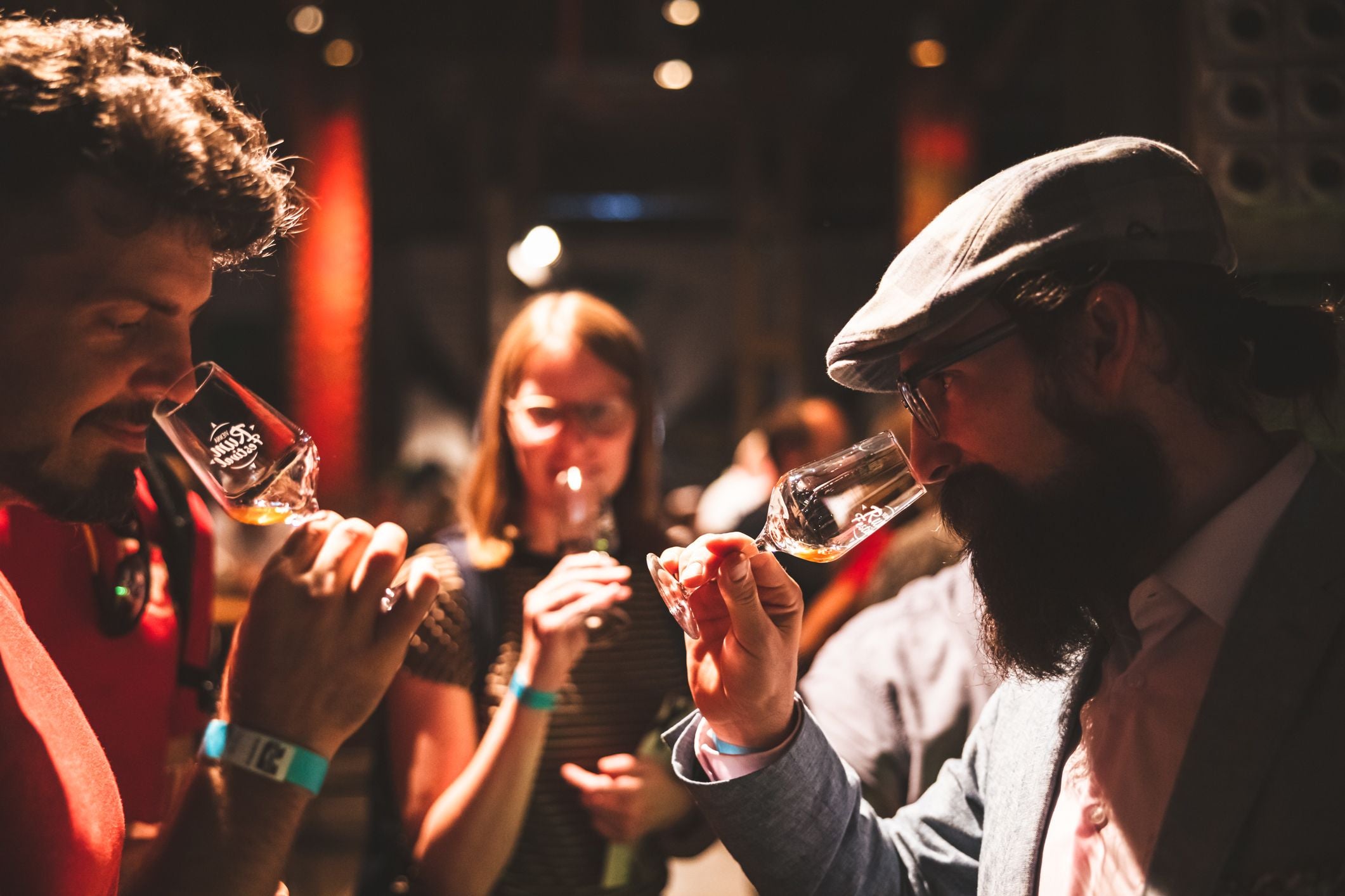 Menschen beim RumFestival riechen an Gläsern mit Rum in stimmungsvollem Licht.