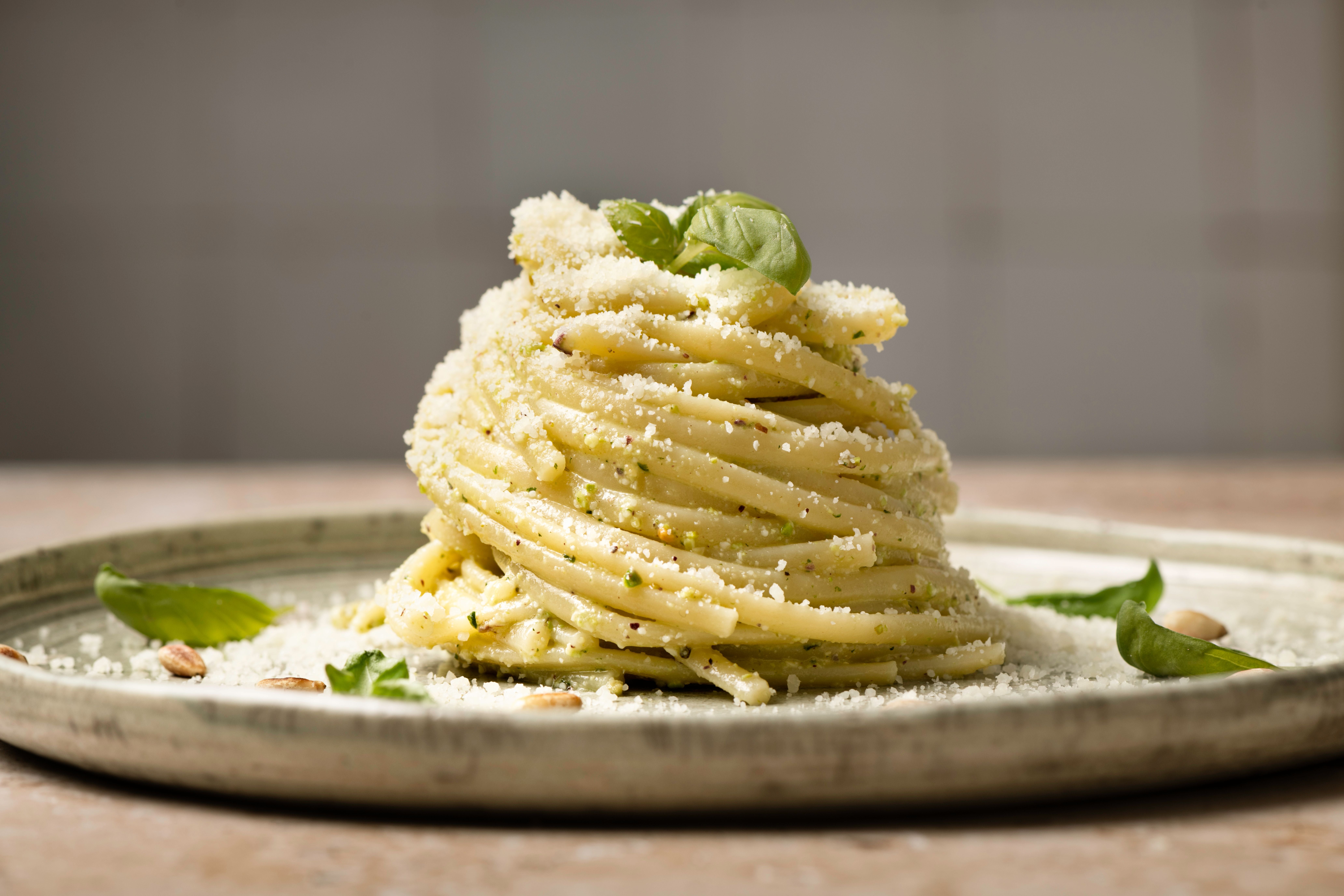 Ein Turm Linguine mit Pesto, Basilikum, Parmesan und Pinienkernen auf einem Teller.