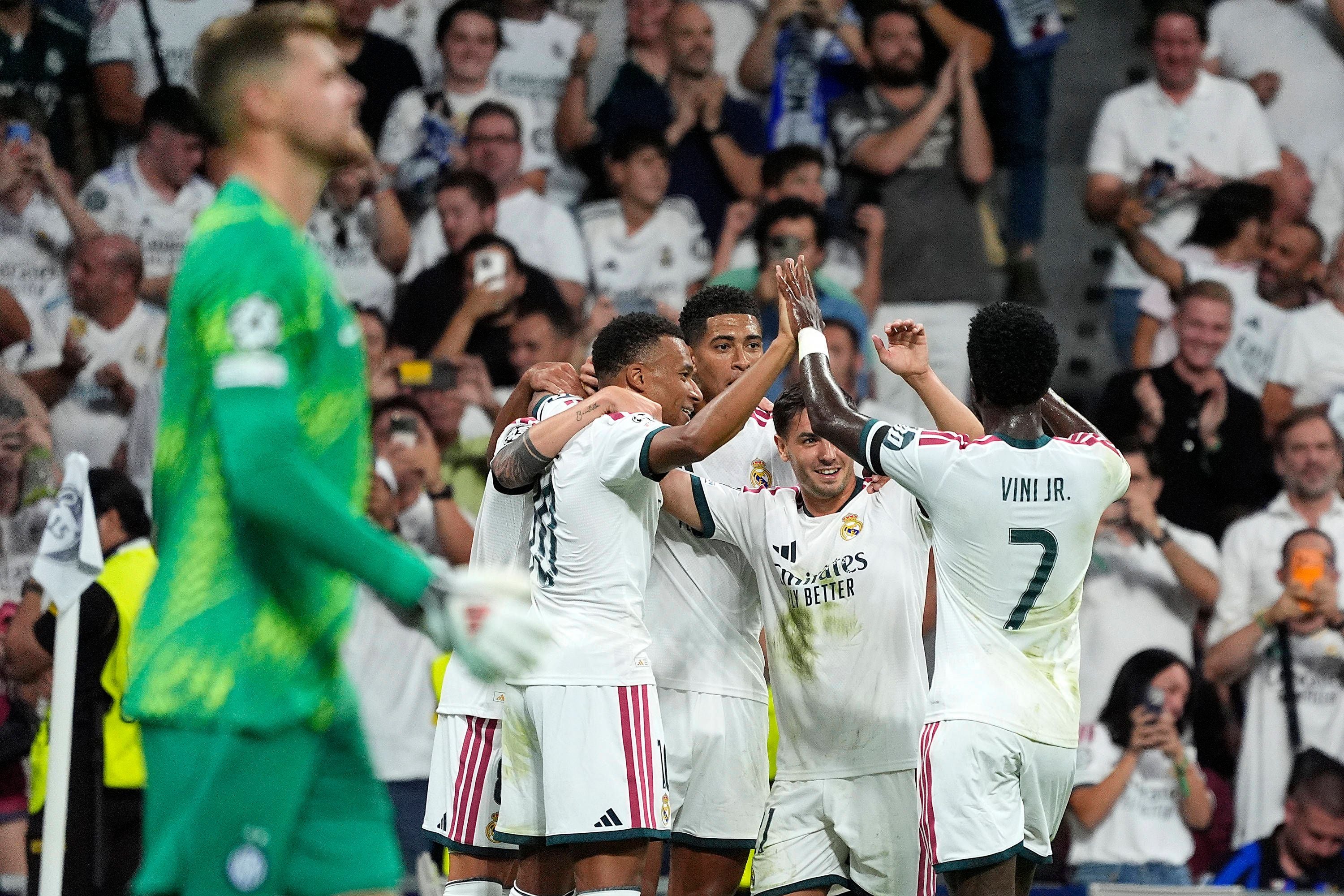 Spieler von Real Madrid feiern ein Tor während eines Champions-League-Spiels, Fans jubeln im Hintergrund.
