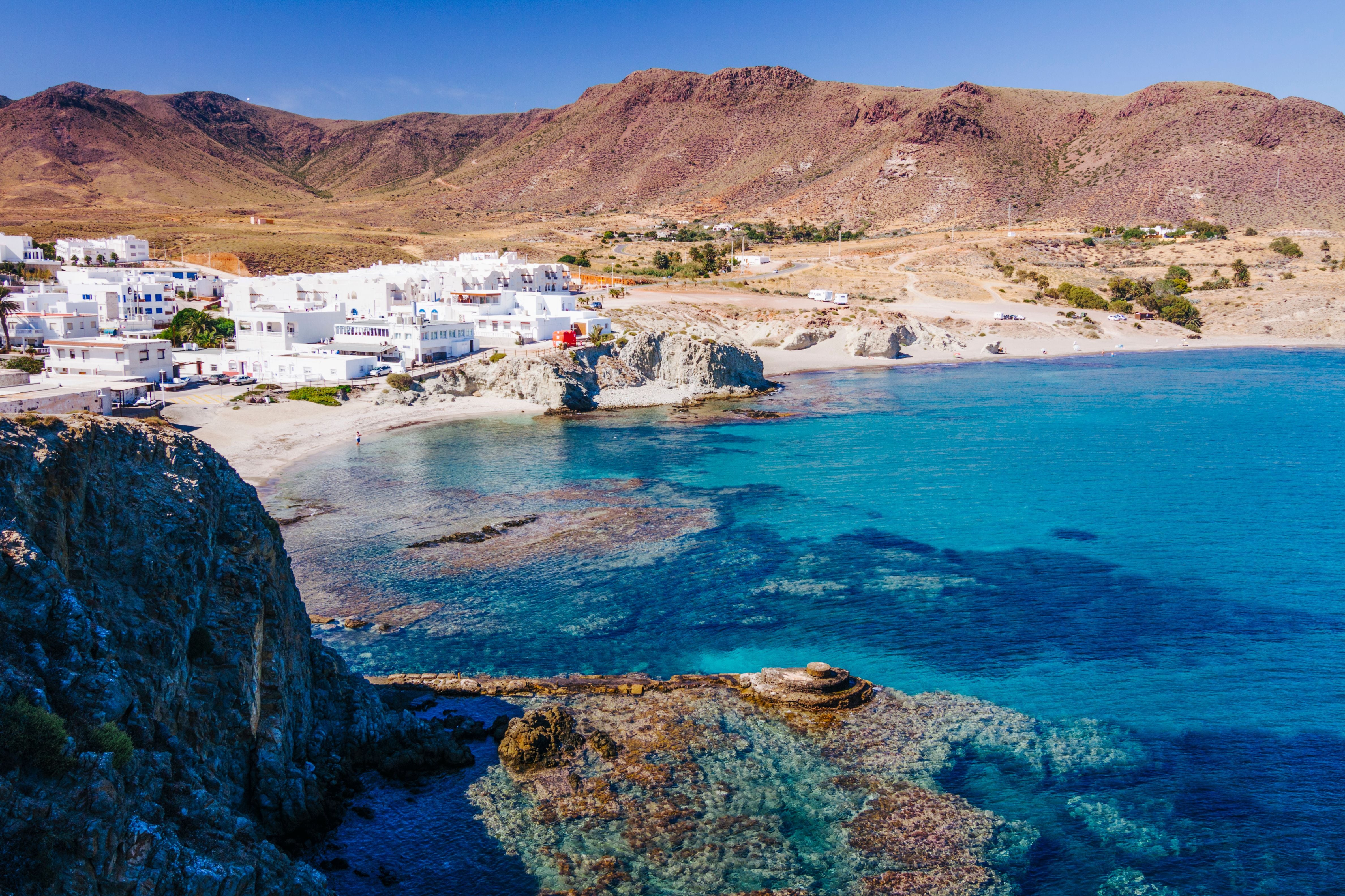 Weißes Fischerdorf an der Küste mit türkisblauem Wasser im Naturpark Cabo de Gata, Spanien.