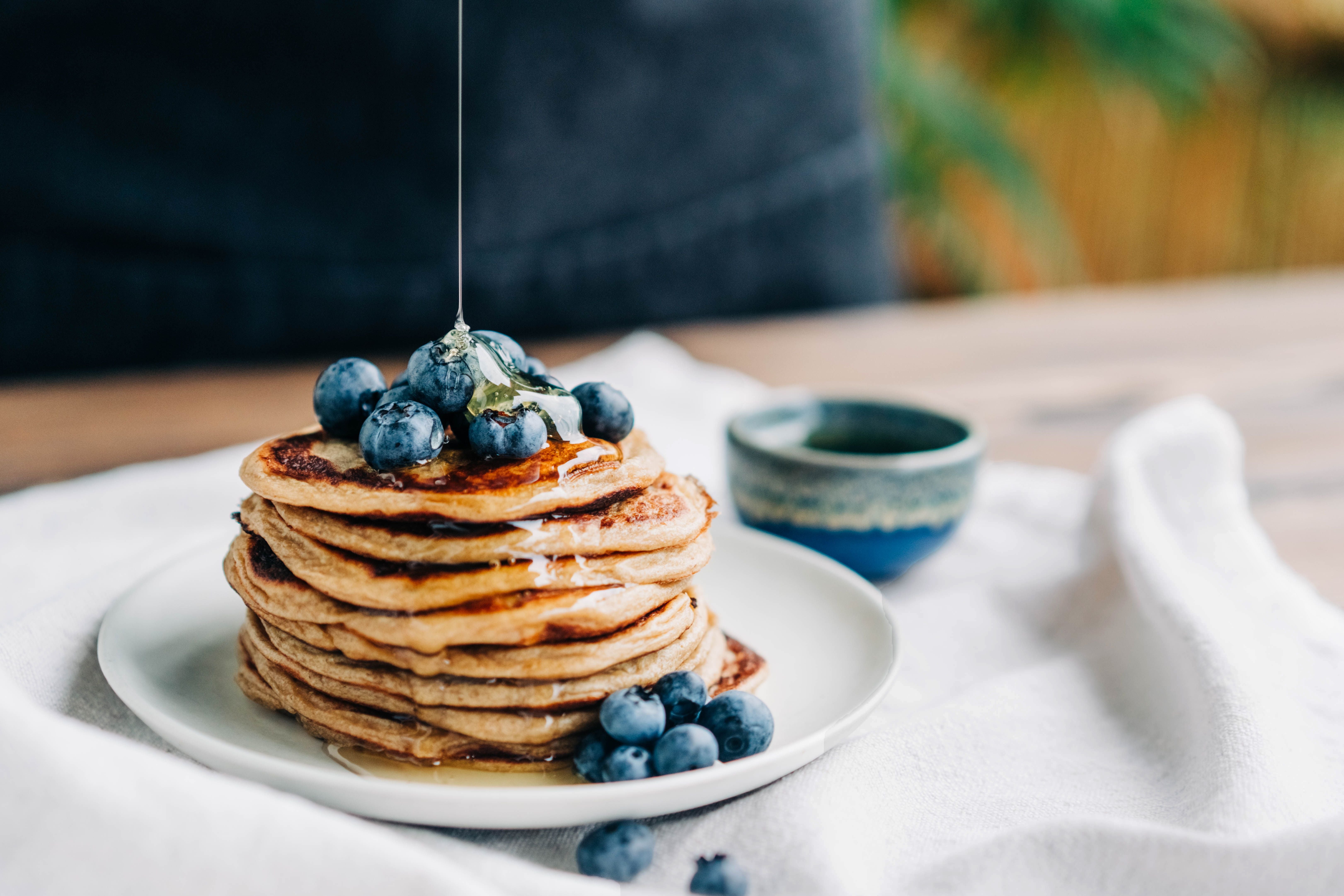 Ein Stapel Pfannkuchen mit Blaubeeren wird mit Honig beträufelt.