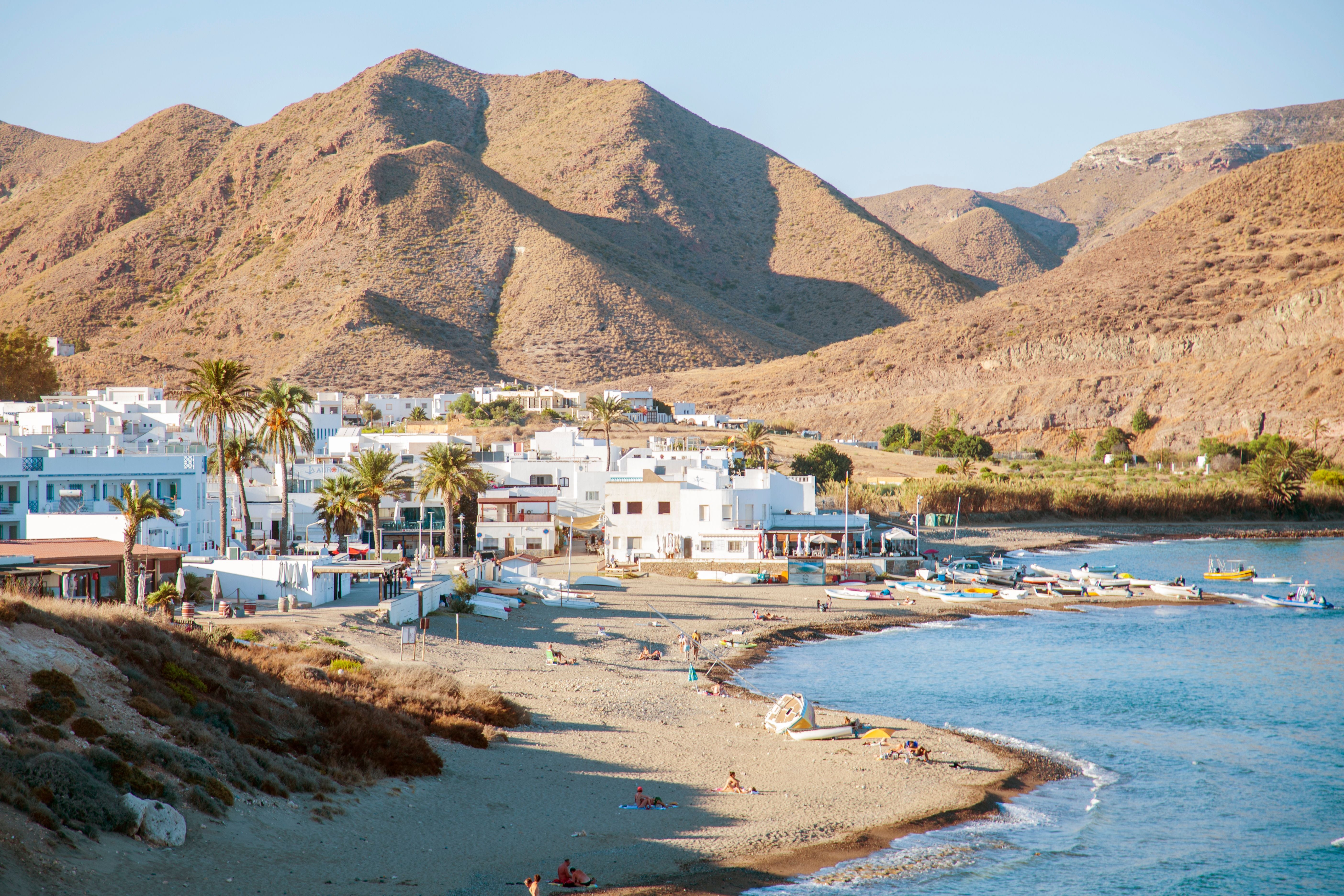 Kleine Strandbucht mit weißen Häusern, Booten und Bergen in Cabo de Gata am Mittelmeer.