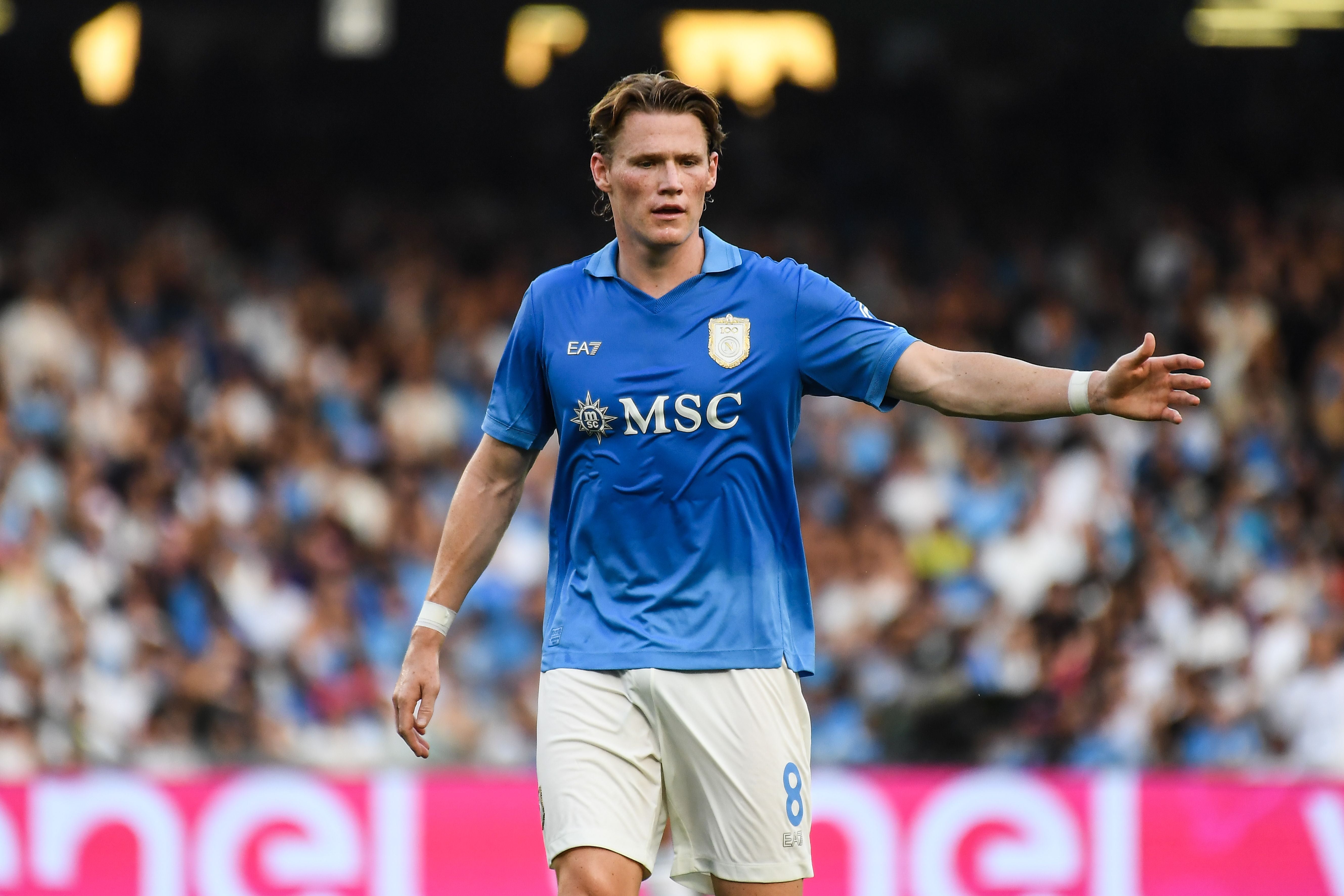 Ein Fußballspieler im blauen Trikot von SSC Napoli gestikuliert während eines Spiels im Stadion.