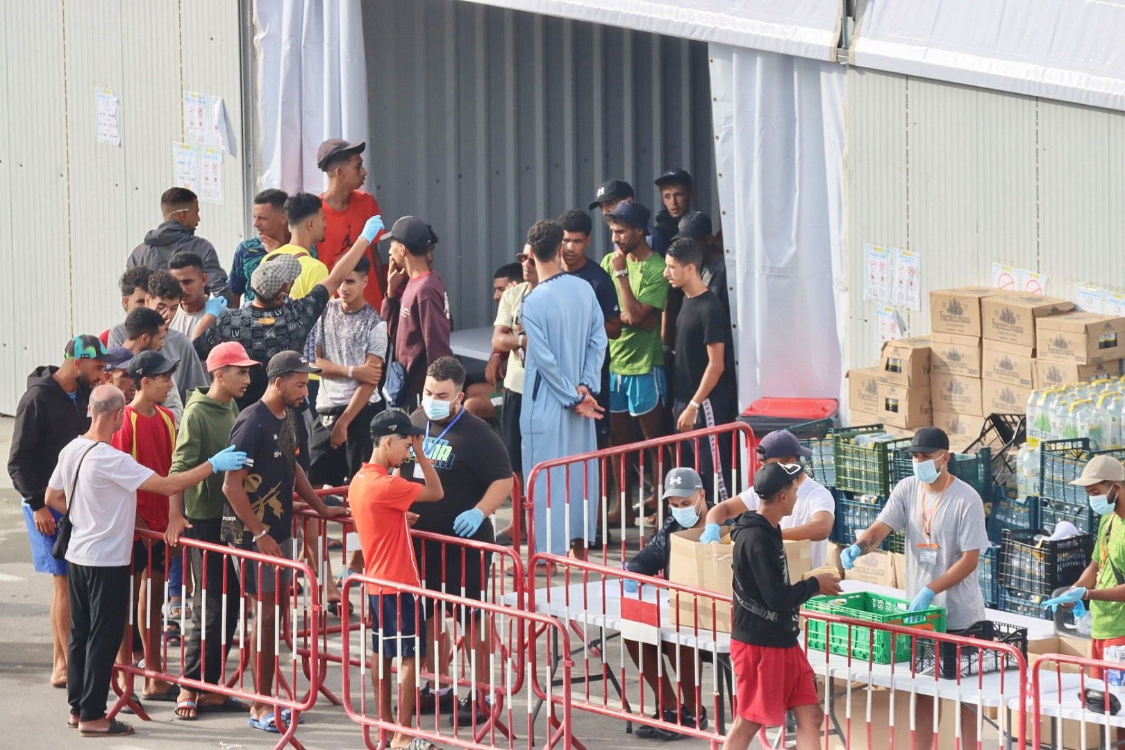 Eine Gruppe Migranten steht an einer Essensausgabe vor einem temporären Zentrum in Ceuta, Spanien.