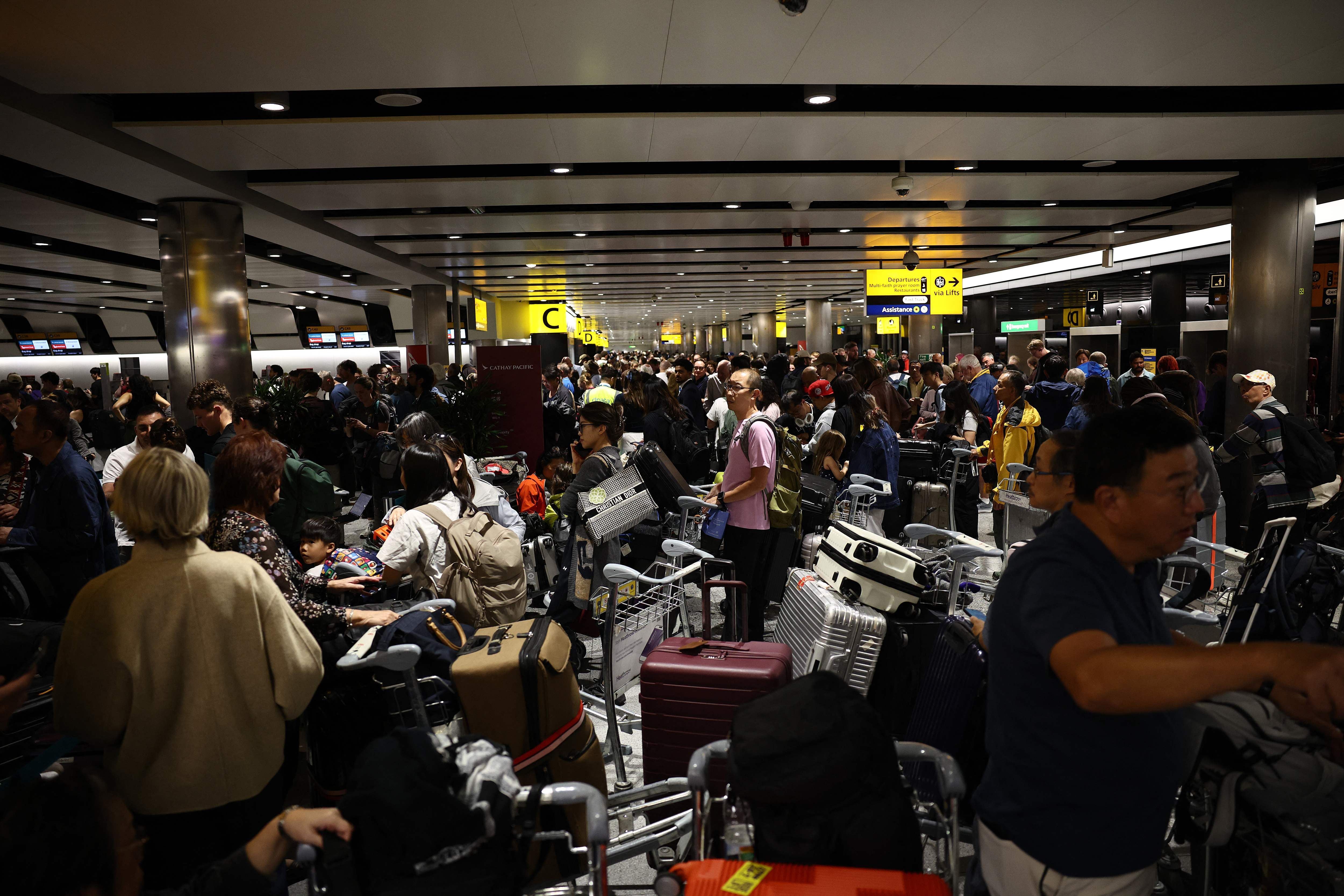 Viele Menschen stehen mit Gepäck und Koffern in einer langen Schlange am Flughafen-Terminal.