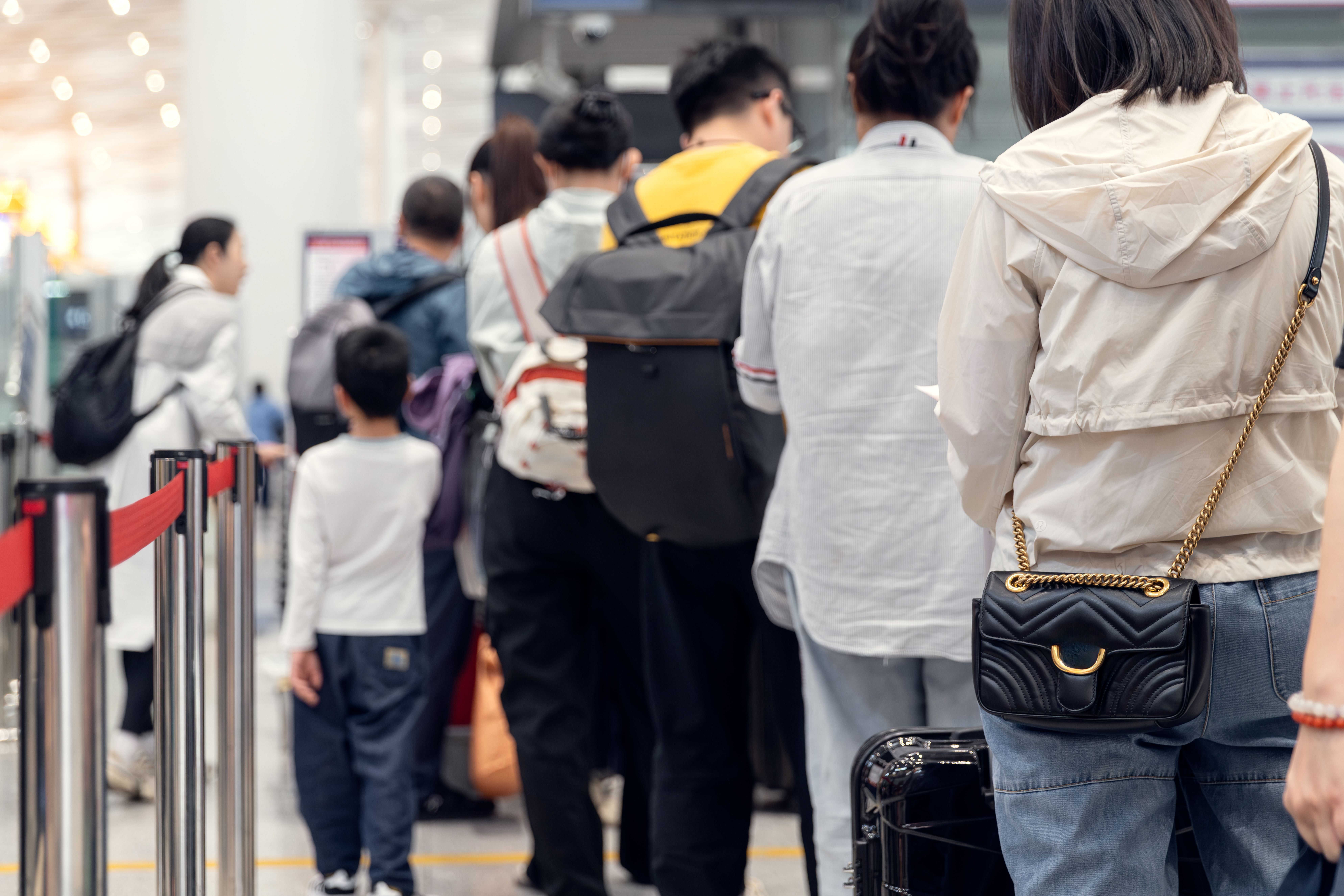 Menschen stehen im Flughafen in einer Schlange zum Check-in mit Gepäck und Rucksäcken.