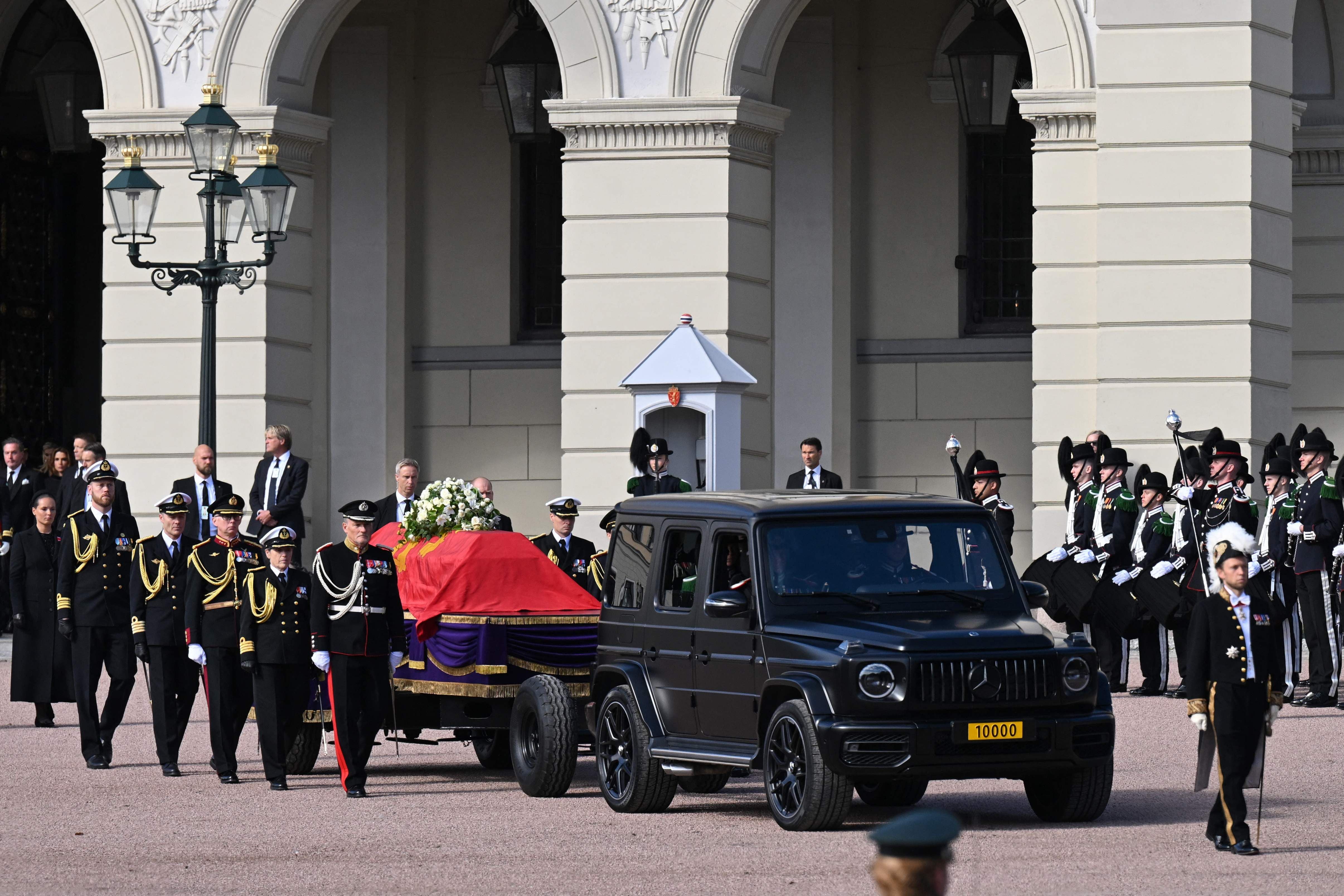 Ein festlicher Trauerzug mit Sarg und Militär eskortiert vor dem königlichen Palast in Oslo.
