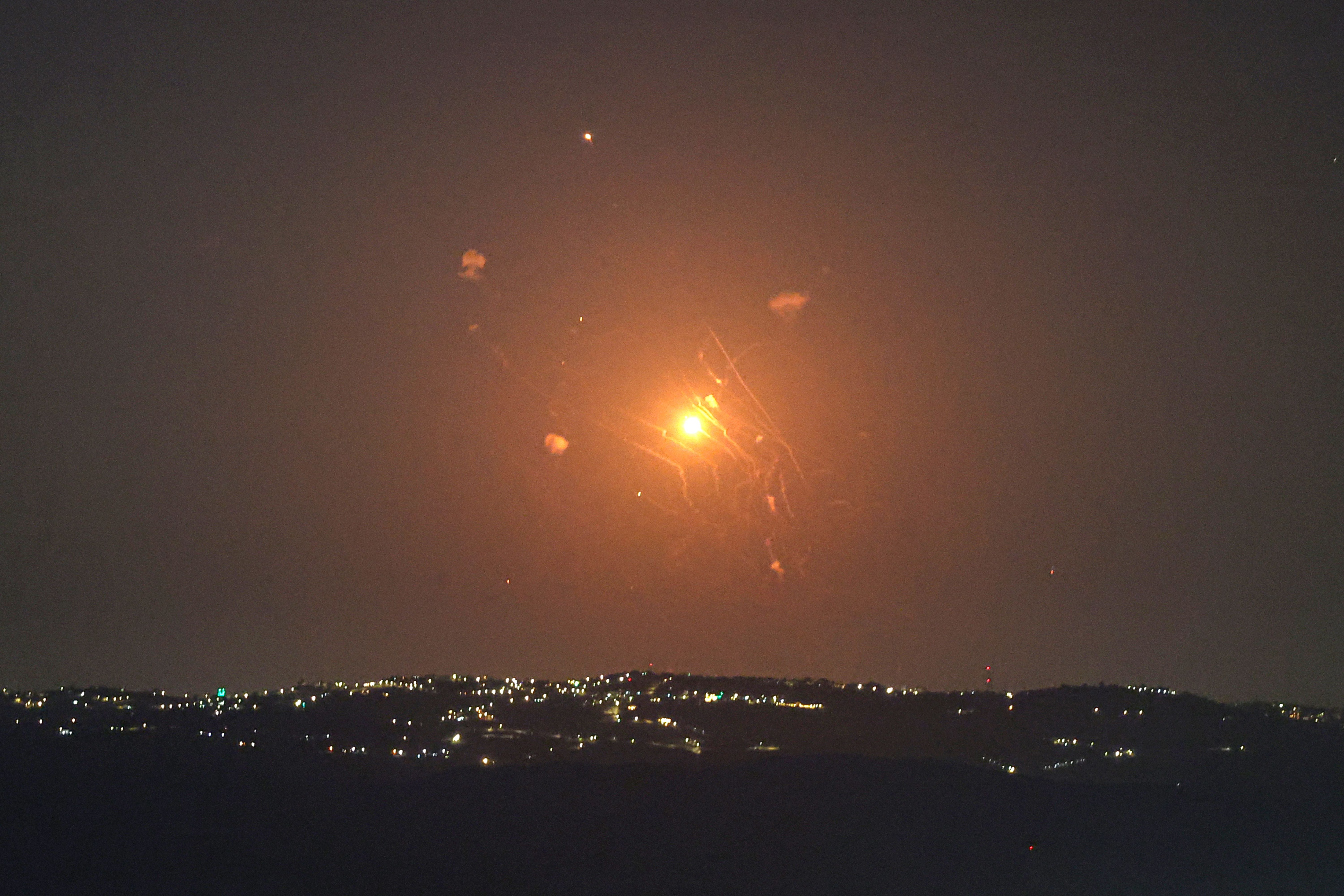 Leuchtspur eines Abfangraketenstarts bei Nacht über beleuchteter Stadtlandschaft.