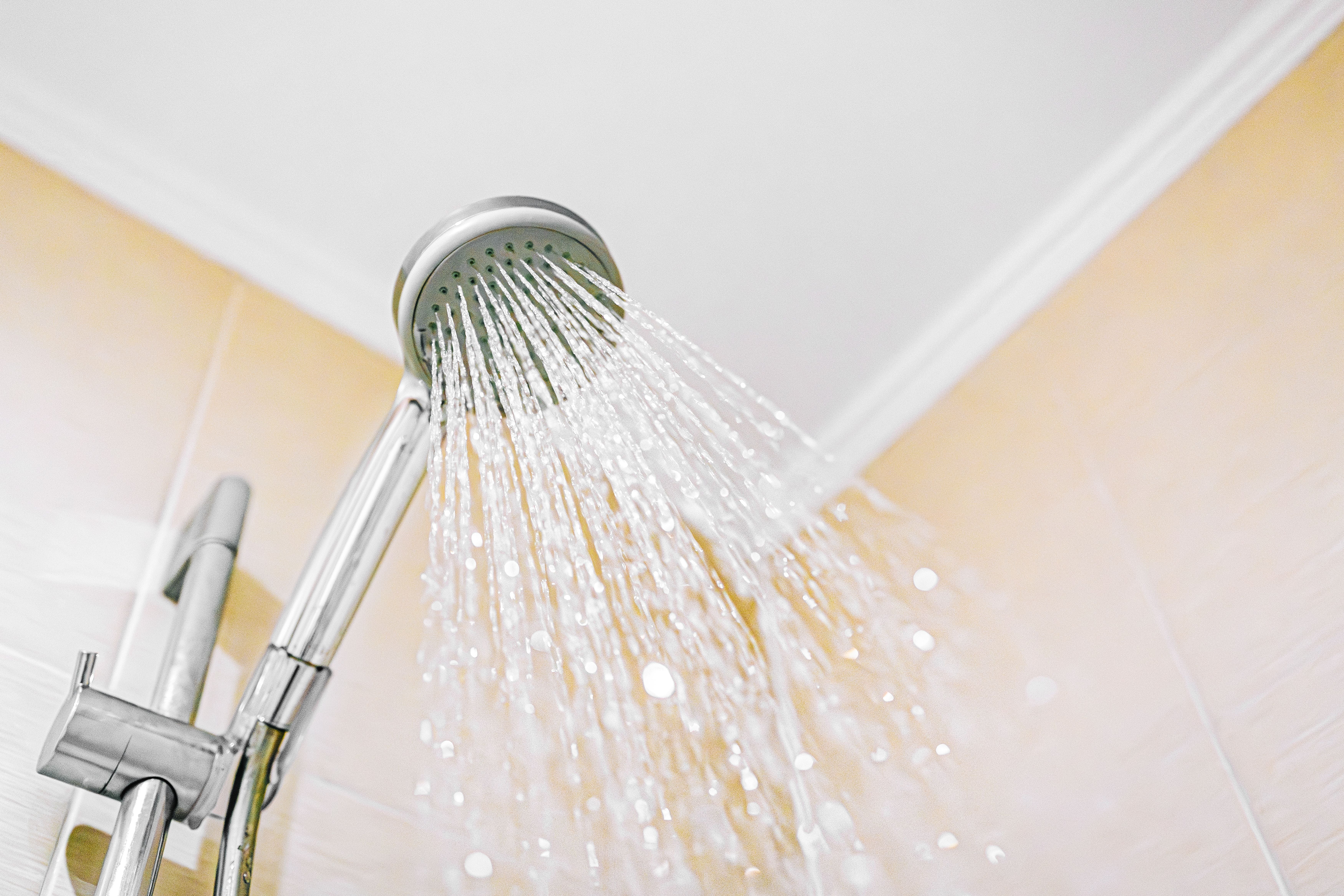 Duschkopf sprüht Wasser in einem Badezimmer.