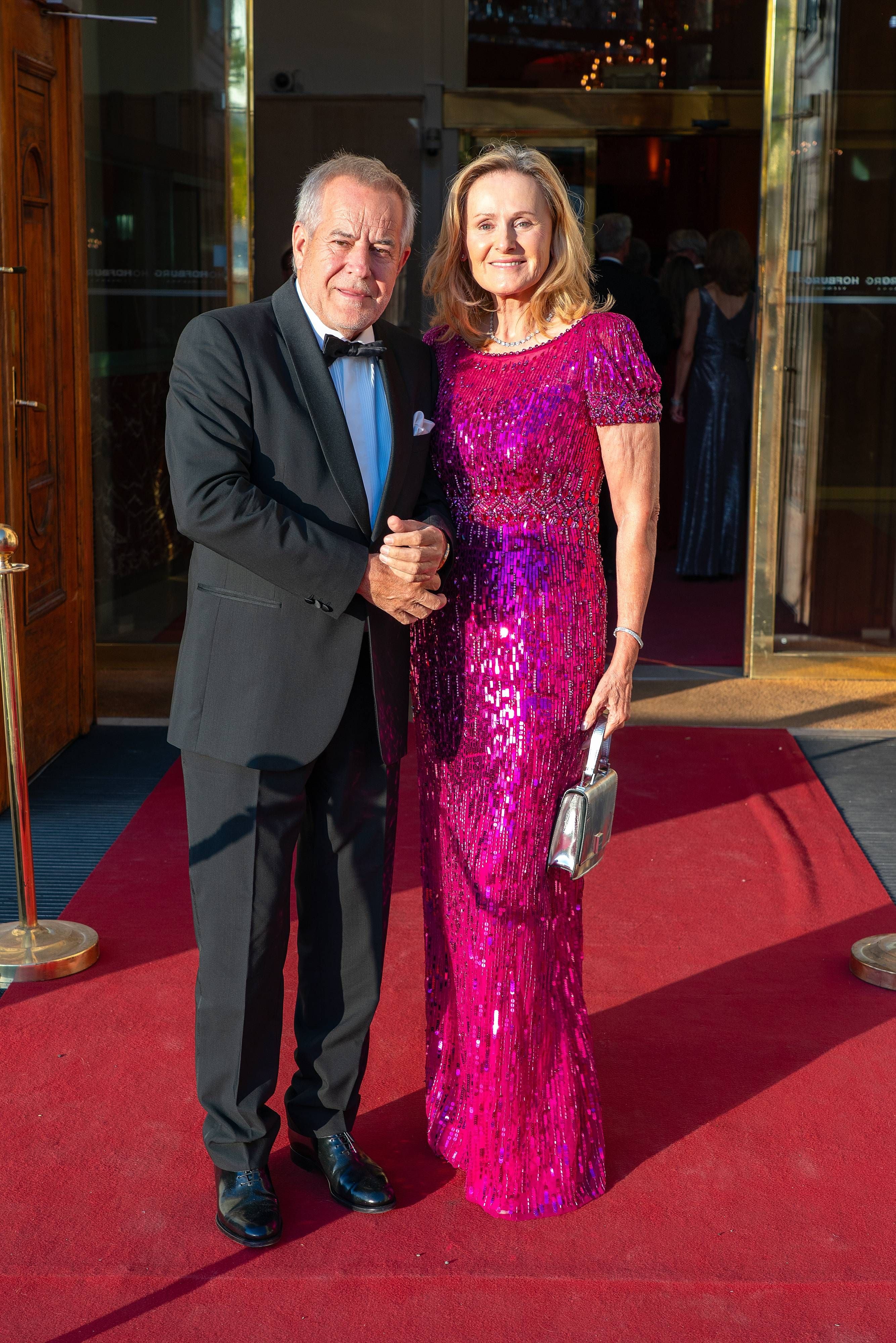 Ein elegant gekleidetes Paar posiert auf dem roten Teppich bei einer Gala-Veranstaltung.