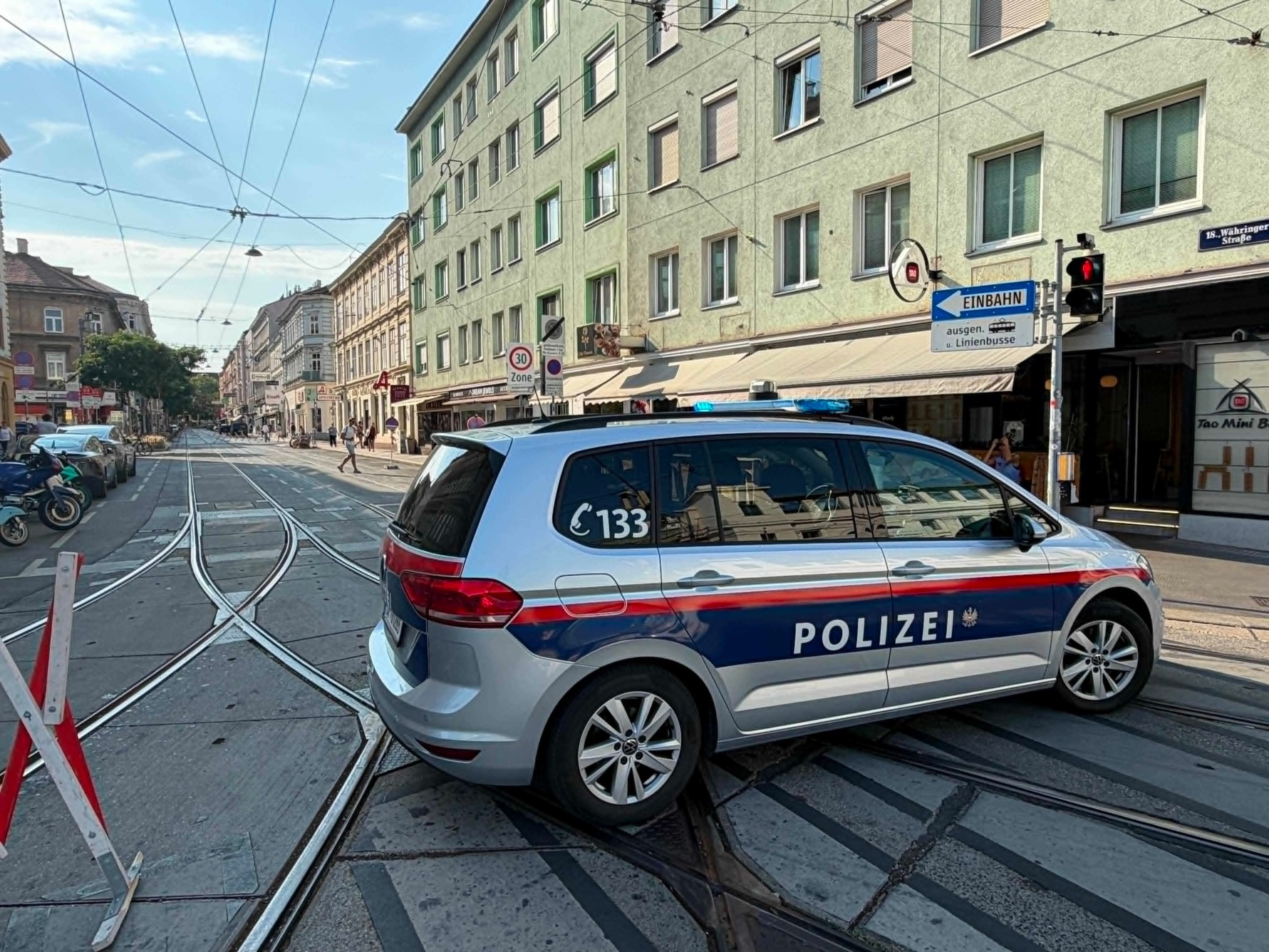 Ein österreichisches Polizeiauto blockiert eine Straßenbahntrasse in einer Stadtstraße.
