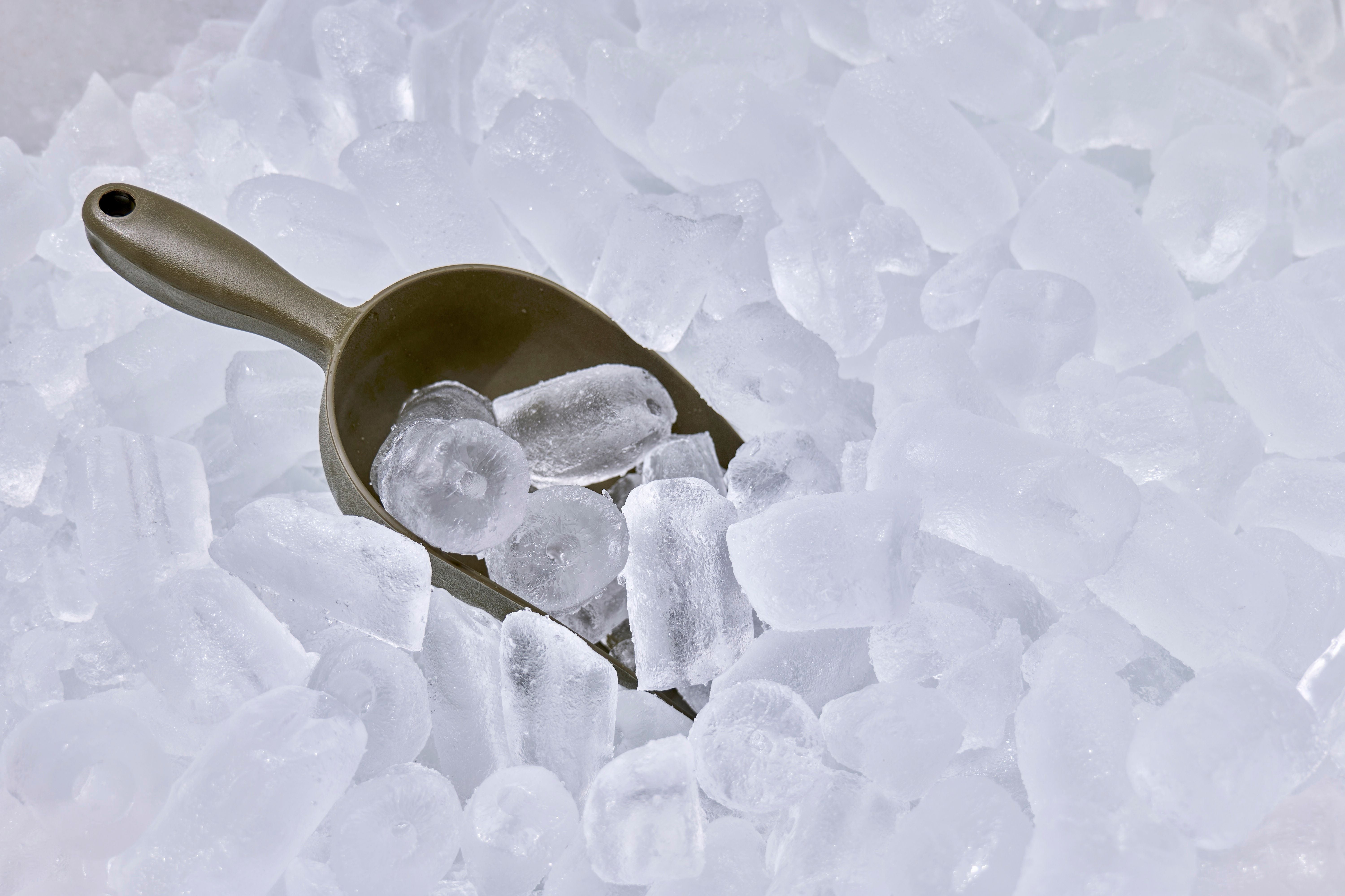 Eisschaufel liegt auf einer großen Menge transparenter Eiswürfel.