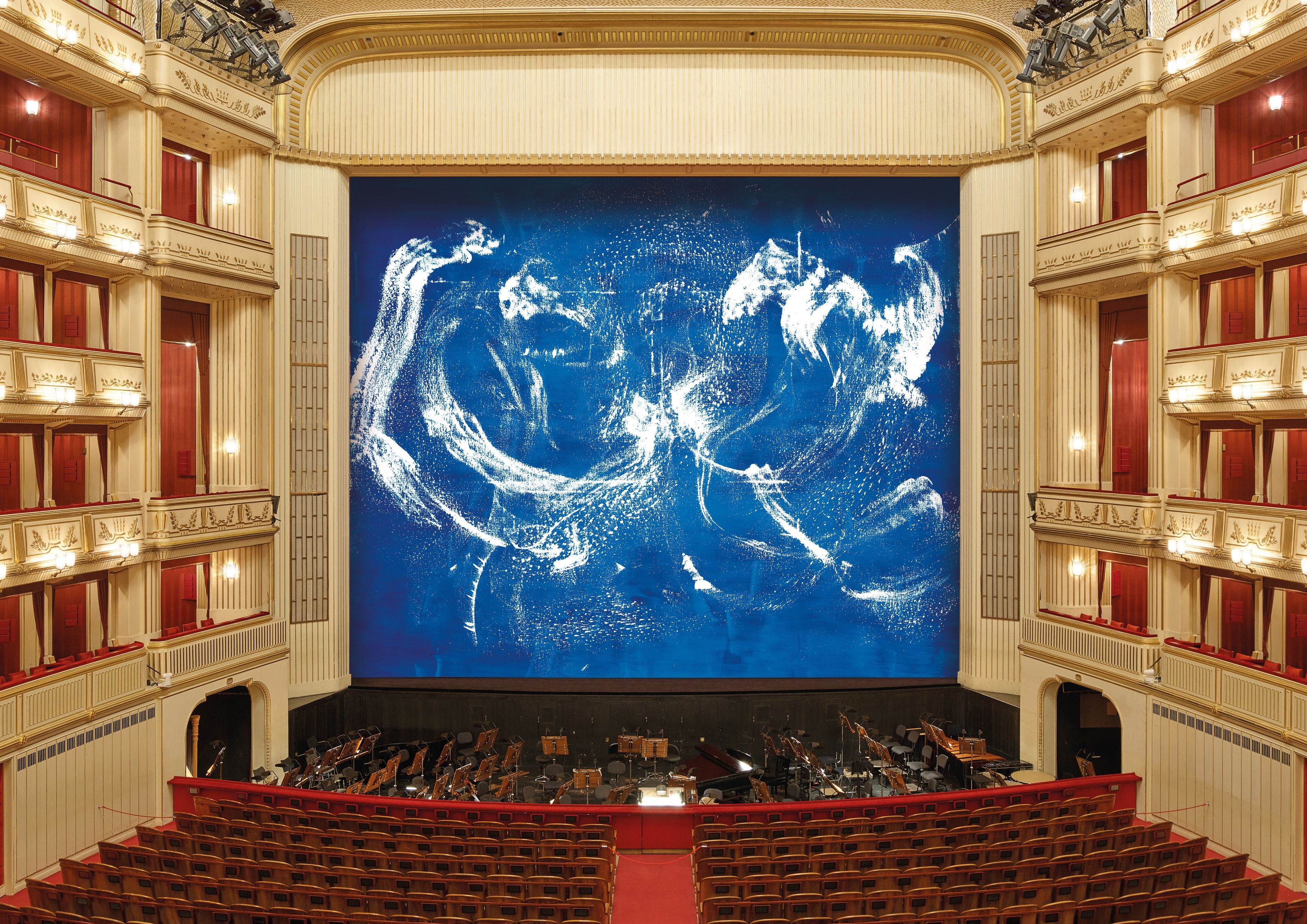 Blick in ein Opernhaus mit dem blauen Eiserner Vorhang von Herbert Brandl auf der Bühne.