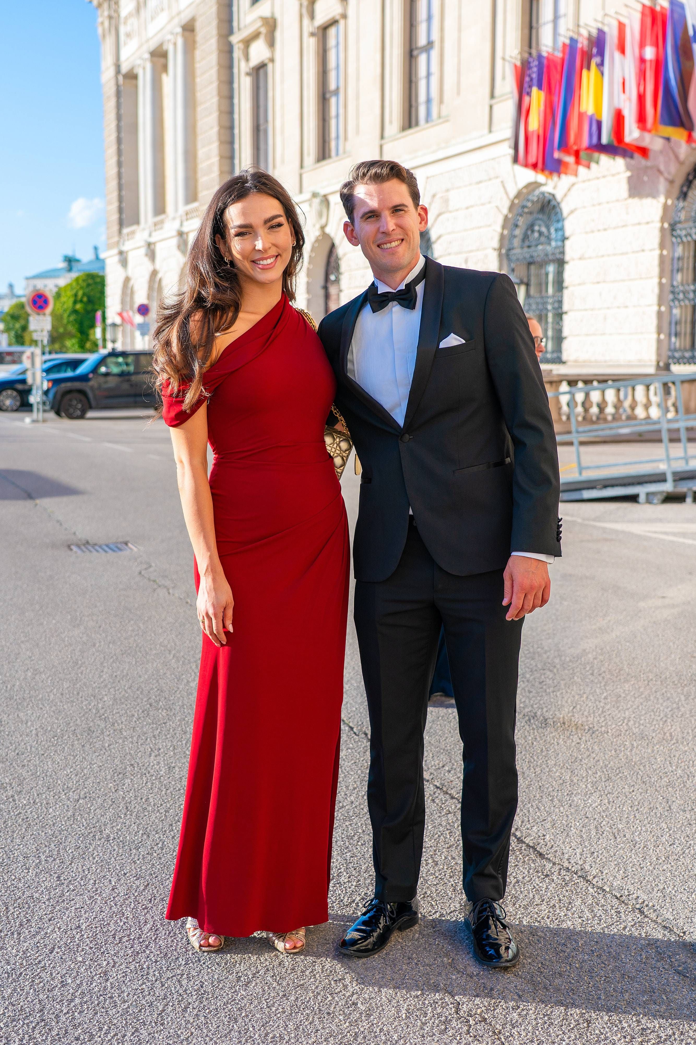 Ein Paar in Abendgarderobe posiert lächelnd vor der Wiener Hofburg bei einer Gala.