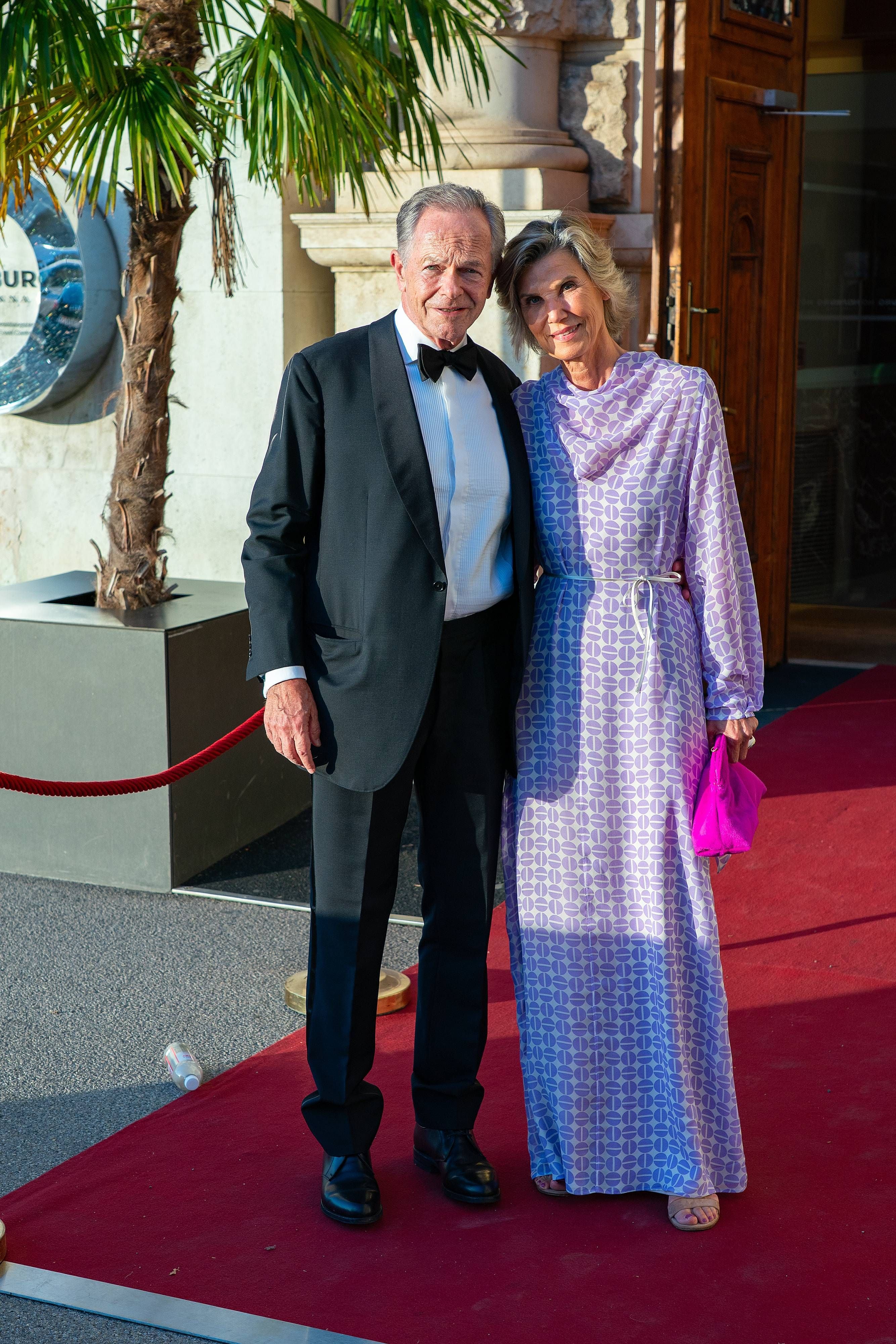 Ein elegant gekleidetes Paar steht zusammen auf einem roten Teppich bei einer Gala-Veranstaltung.
