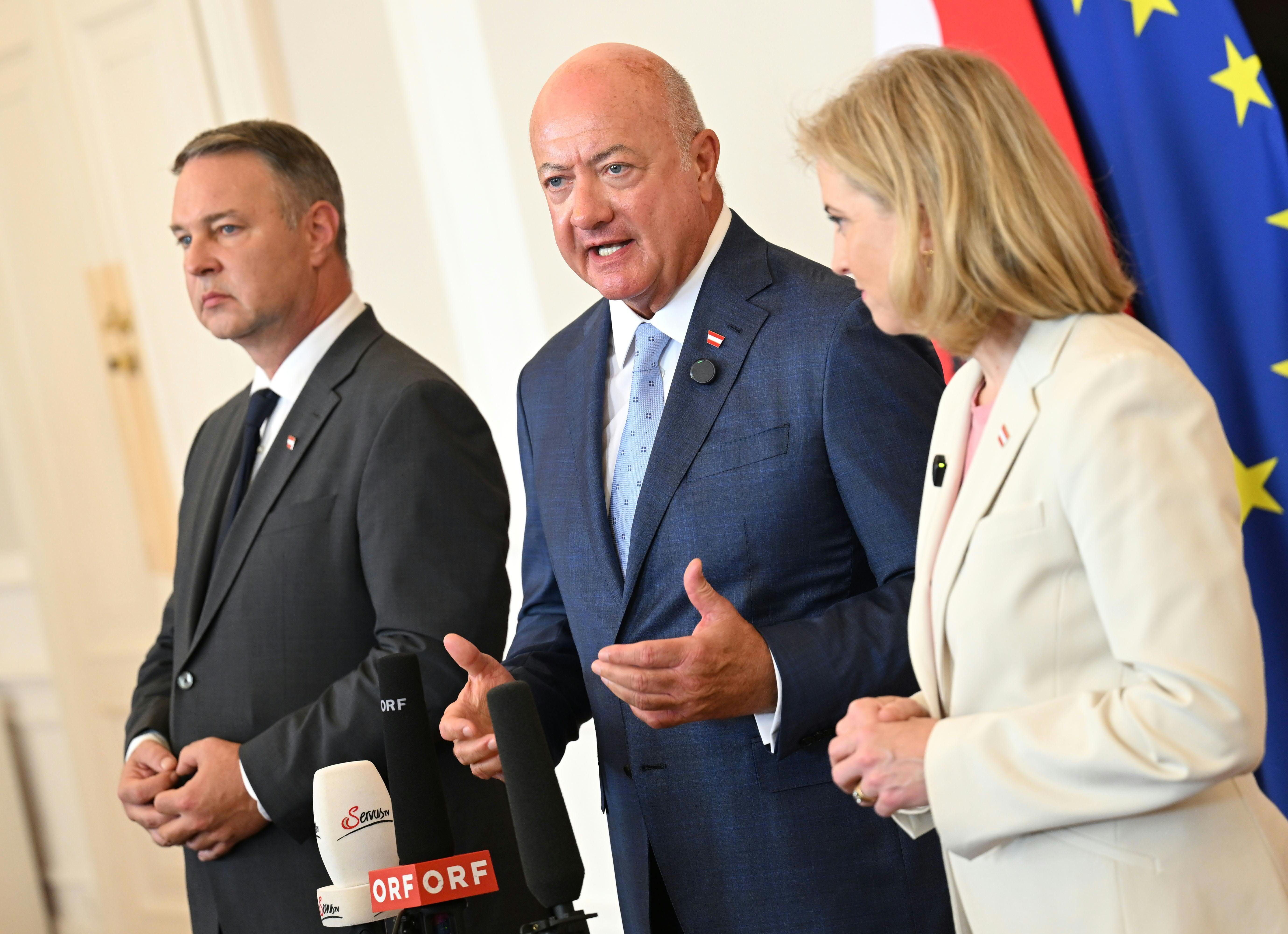 Drei Politiker sprechen im Bundeskanzleramt Wien vor Mikrofonen, EU-Flagge im Hintergrund.