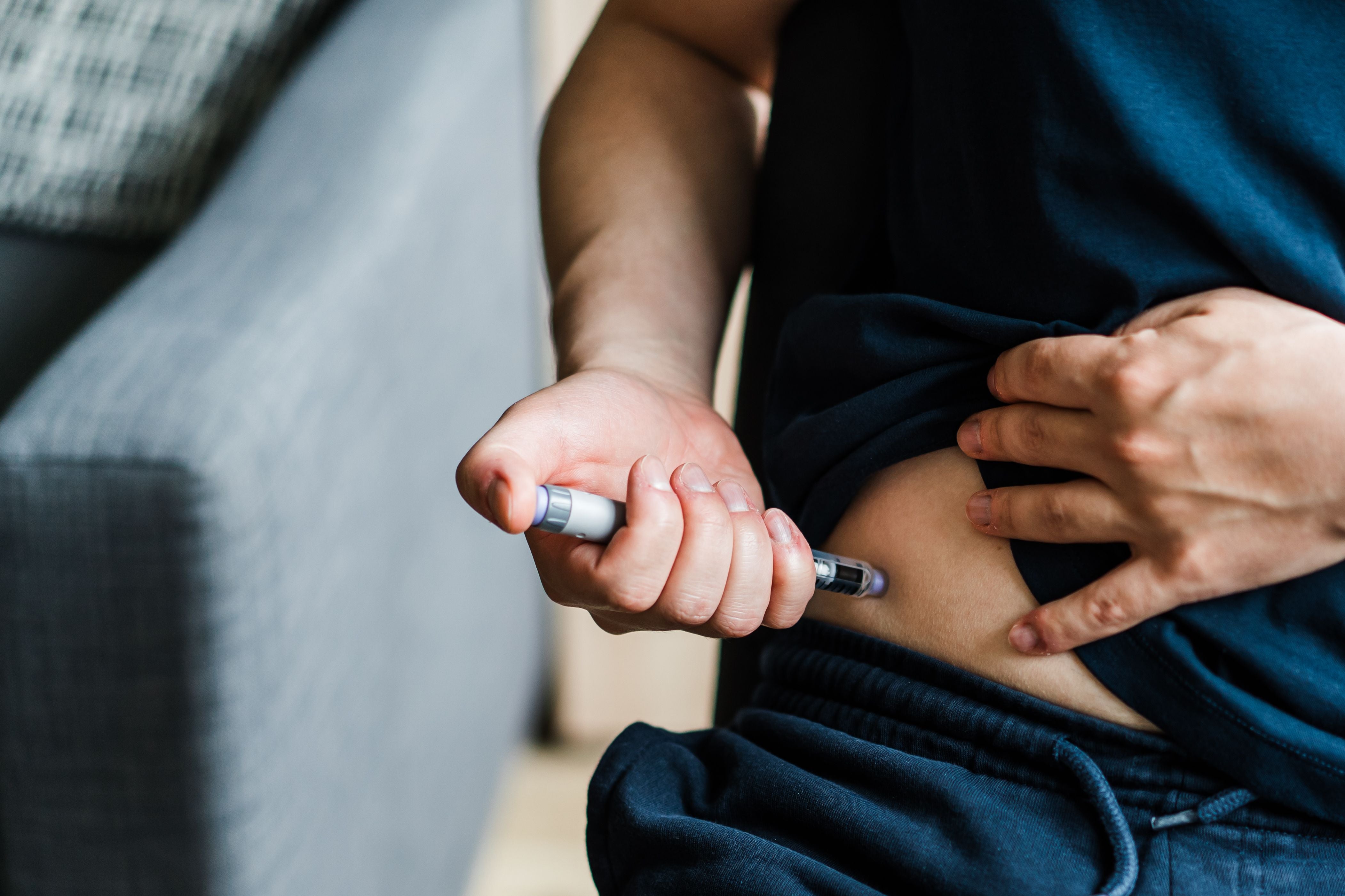 Mann spritzt sich Insulin in den Bauch als Teil der Diabetesbehandlung.