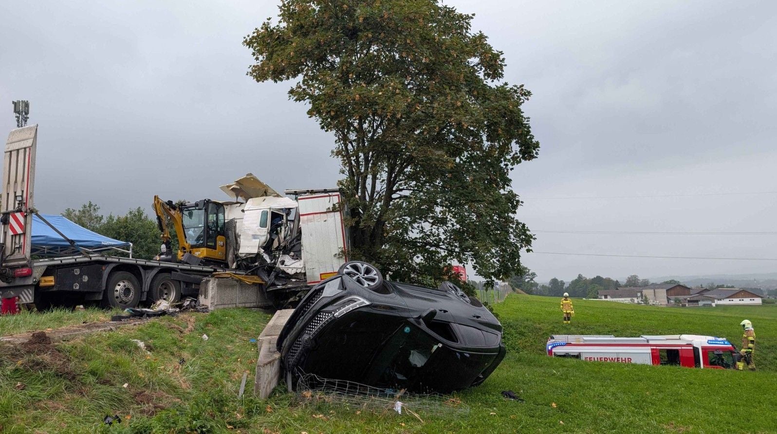 Schwerer Verkehrsunfall mit umgestürztem Auto und beschädigtem LKW, Feuerwehr vor Ort.
